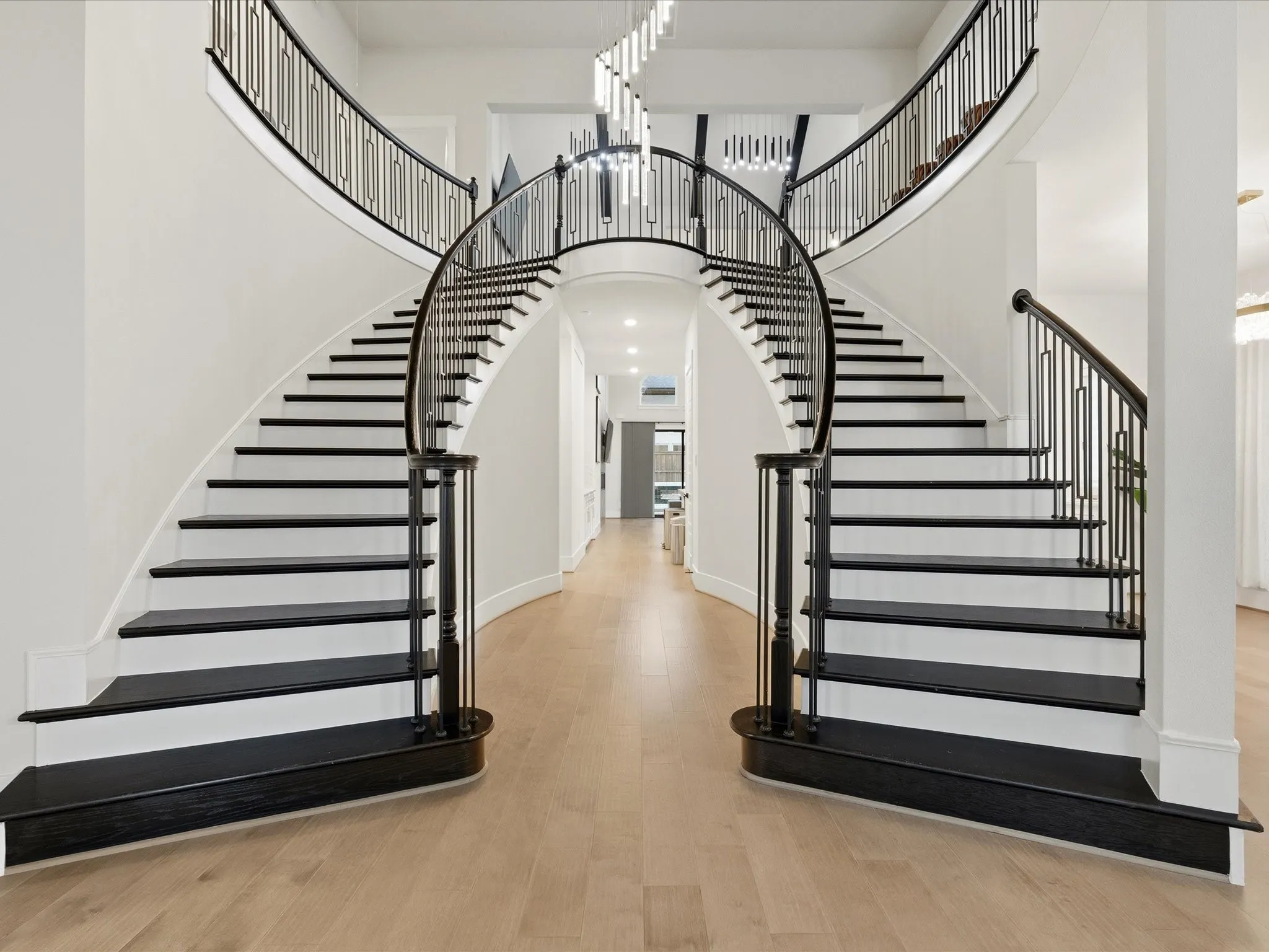 Grand bifurcated staircase featuring dark wood treads and handrails with contemporary metal balusters