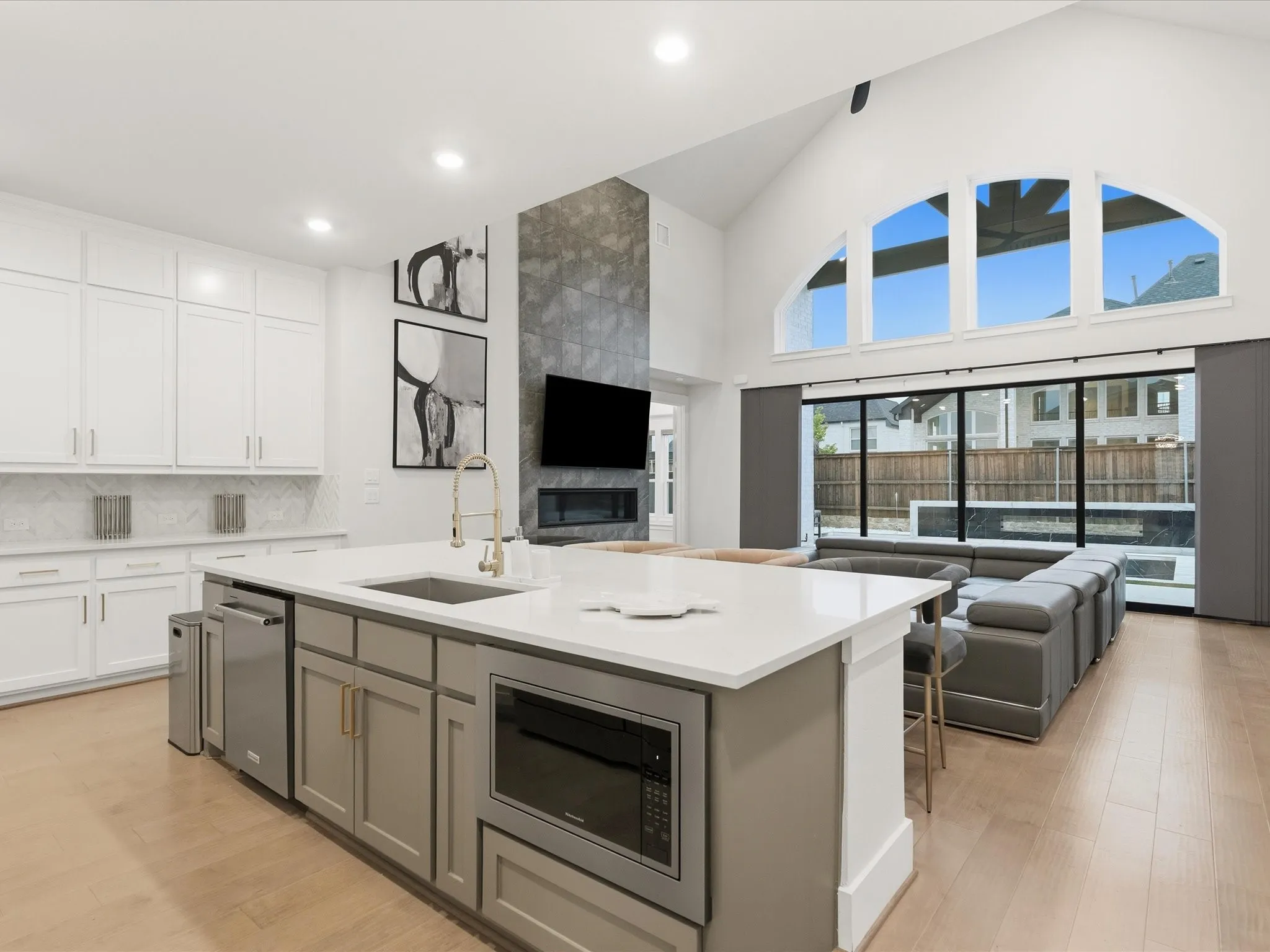 Open-concept living area featuring a vaulted ceiling and an expansive arched window ensemble