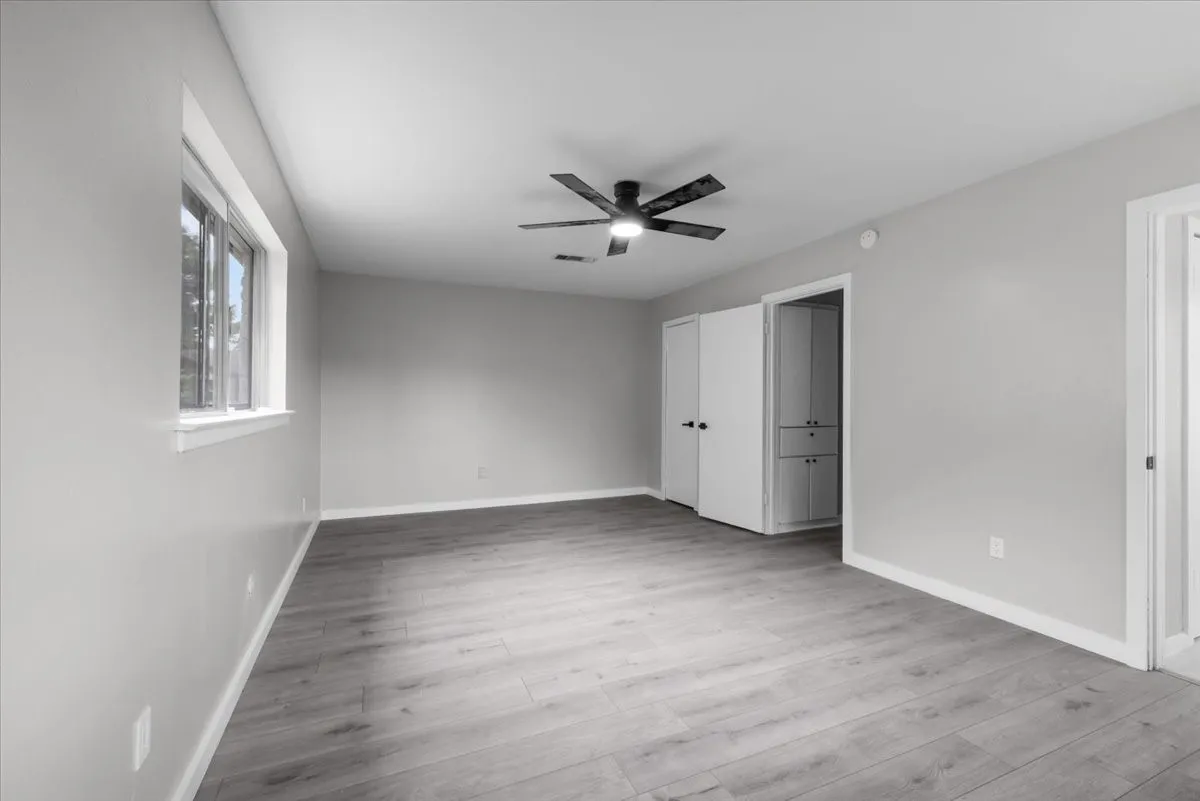 Spacious room featuring wood-finish flooring and a contemporary ceiling fan