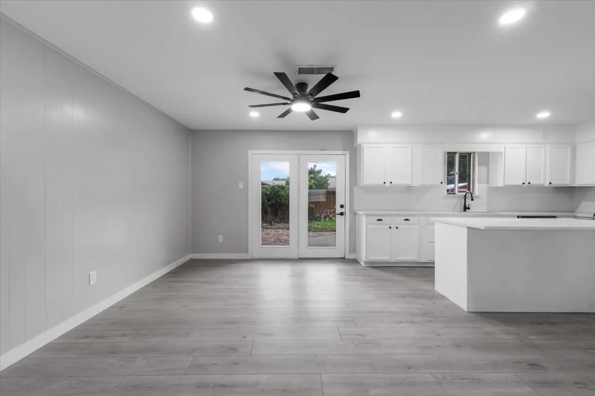 Open-concept kitchen and living area featuring wood-finish flooring, white cabinetry, a kitchen island, recessed lighting, and patio access