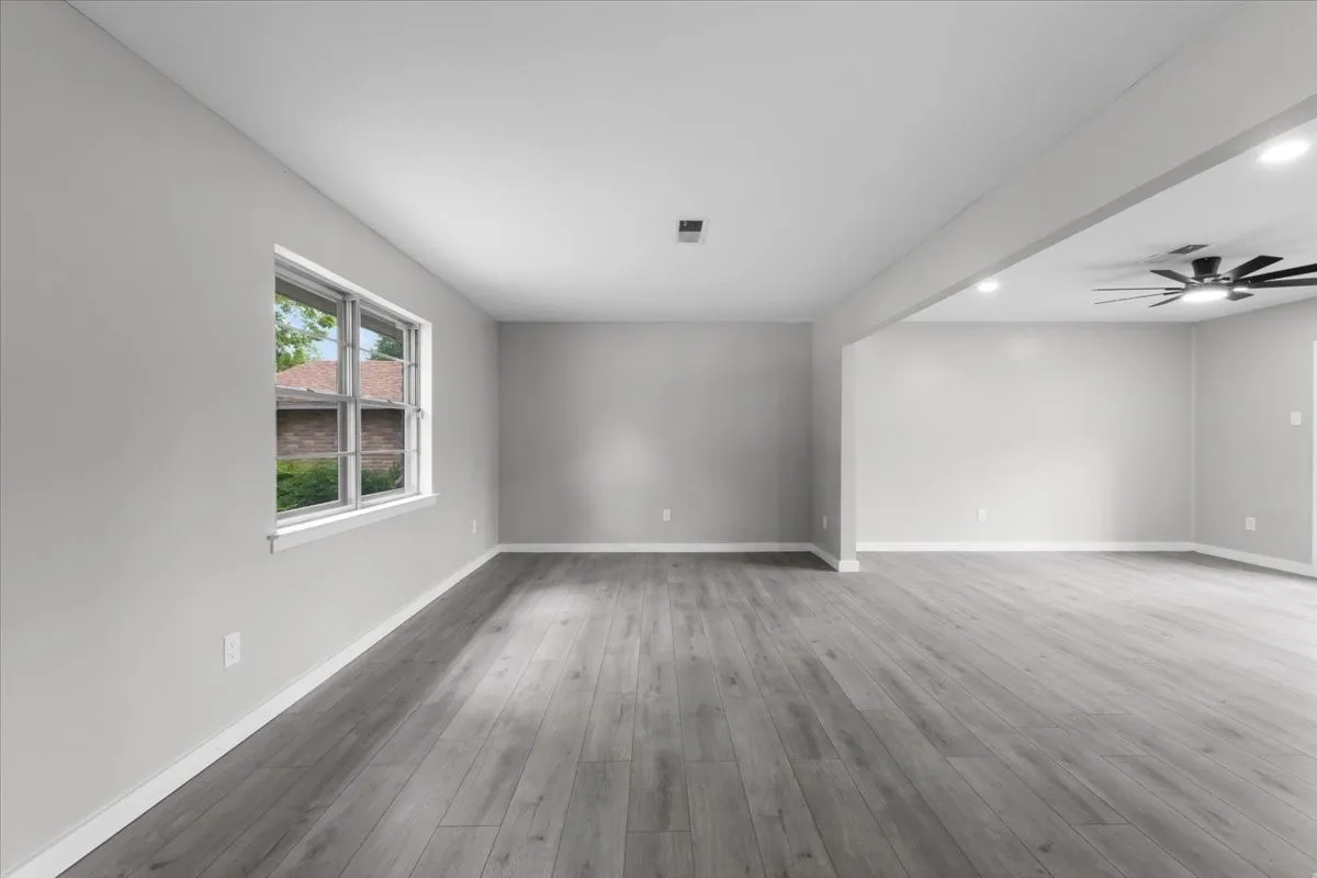 Spacious room with light gray walls and wood-finish flooring