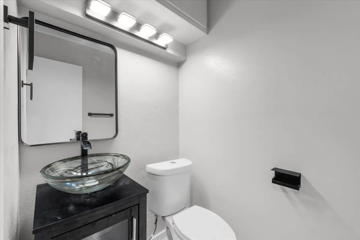 Bathroom featuring a contemporary vessel sink, dark wood-finish vanity, and a wall-mounted rectangular mirror