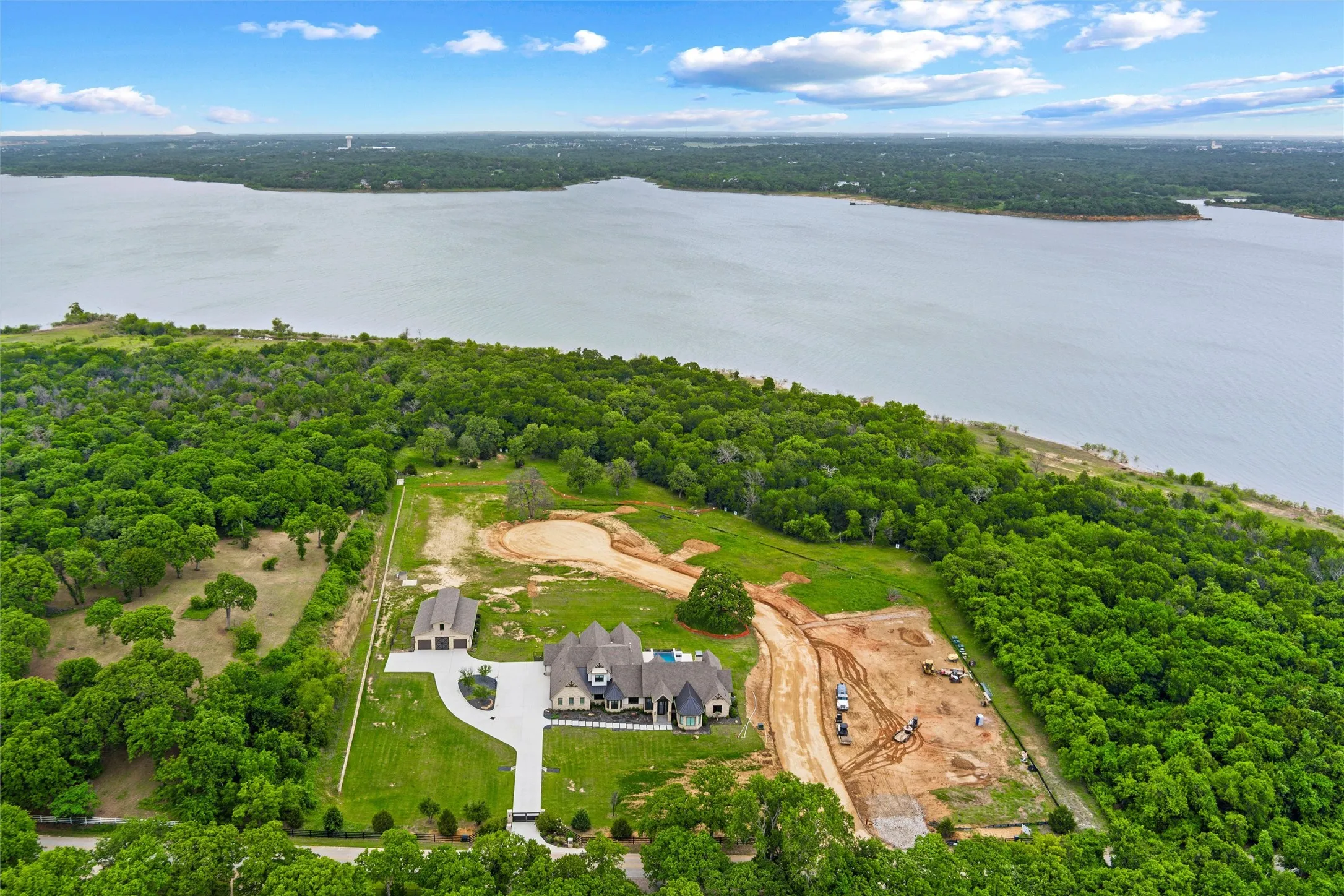 Expansive estate featuring a large main residence, detached garage, private drive, and substantial cleared land