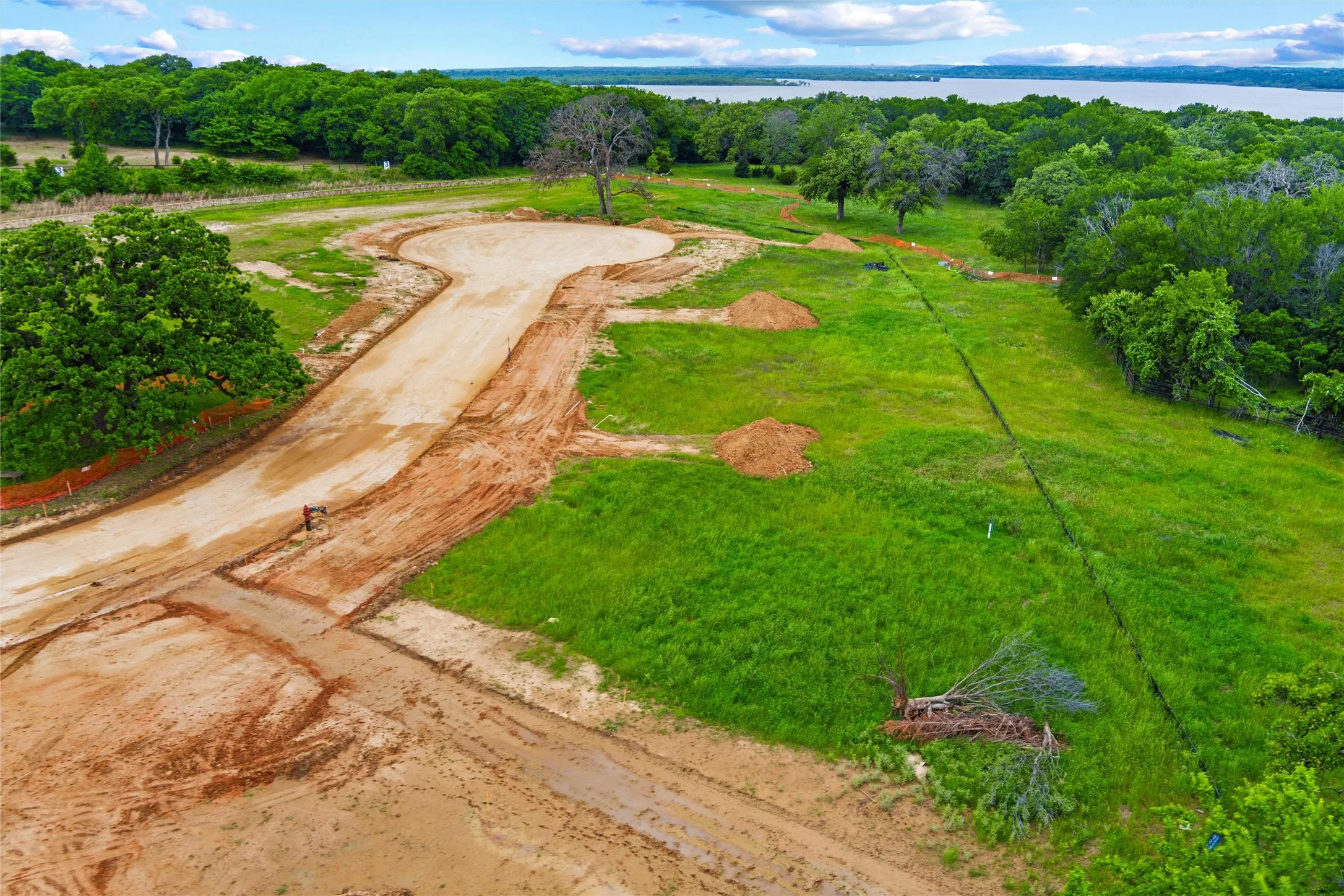 Graded cul-de-sac with undeveloped lots and a backdrop of mature trees