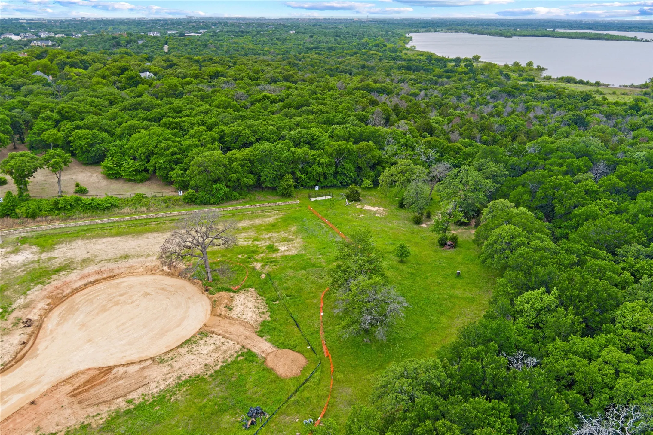 Expansive cleared land parcel offering substantial development potential, bordered by lush mature trees