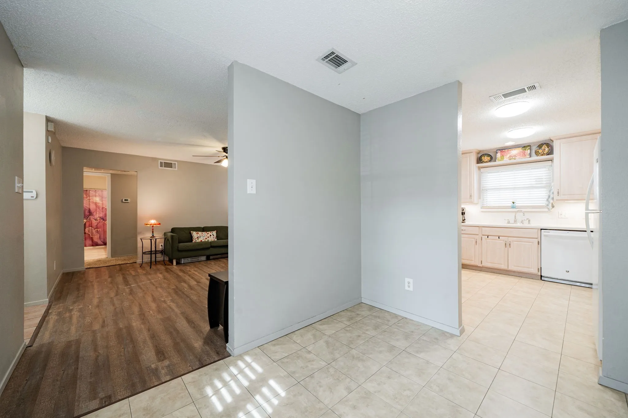 Transitional interior space featuring a partial wall separating distinct flooring types
