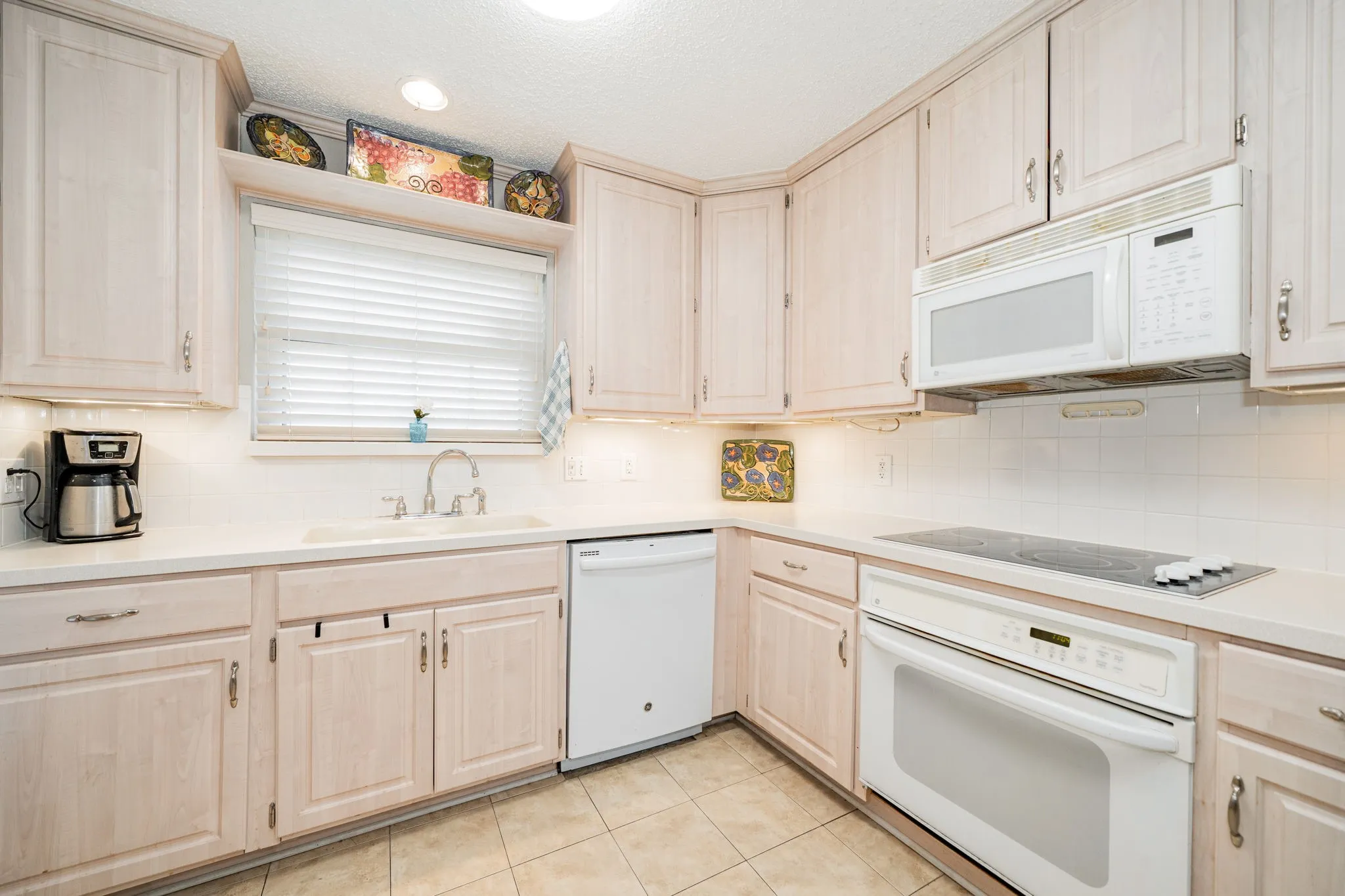 Kitchen featuring light-toned cabinetry, a built-in oven, and an electric cooktop