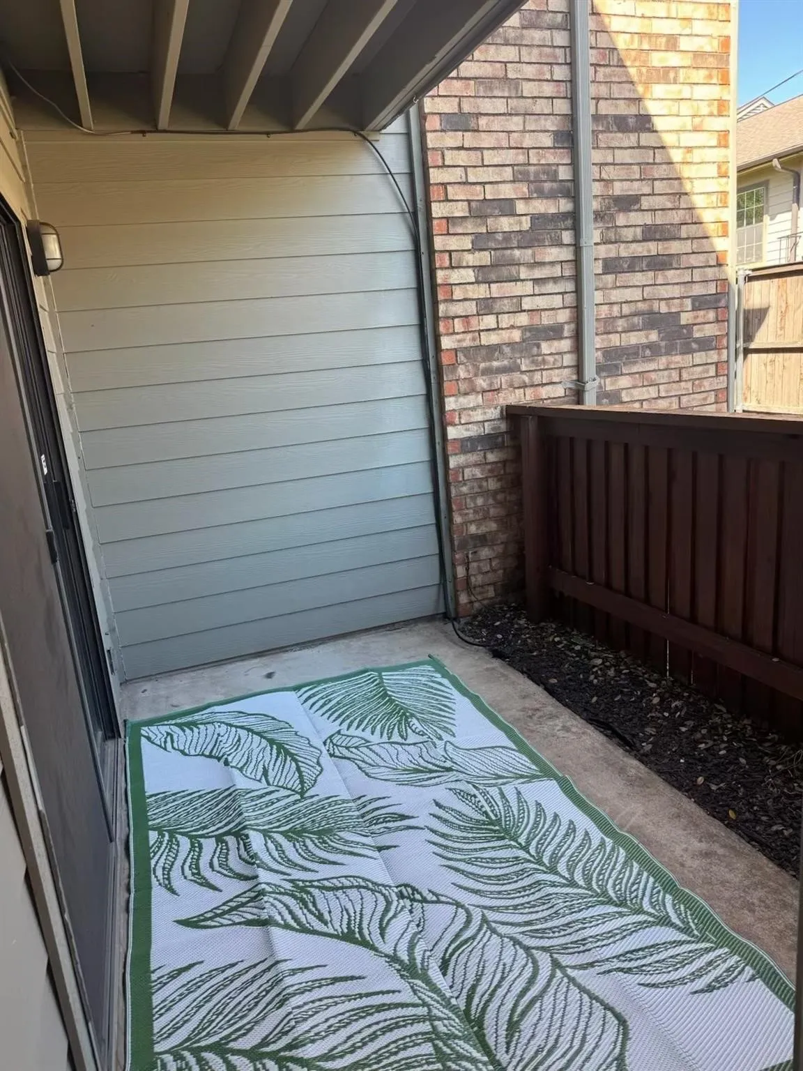 Outdoor patio featuring a concrete surface, horizontal siding, brick wall, and a wooden fence