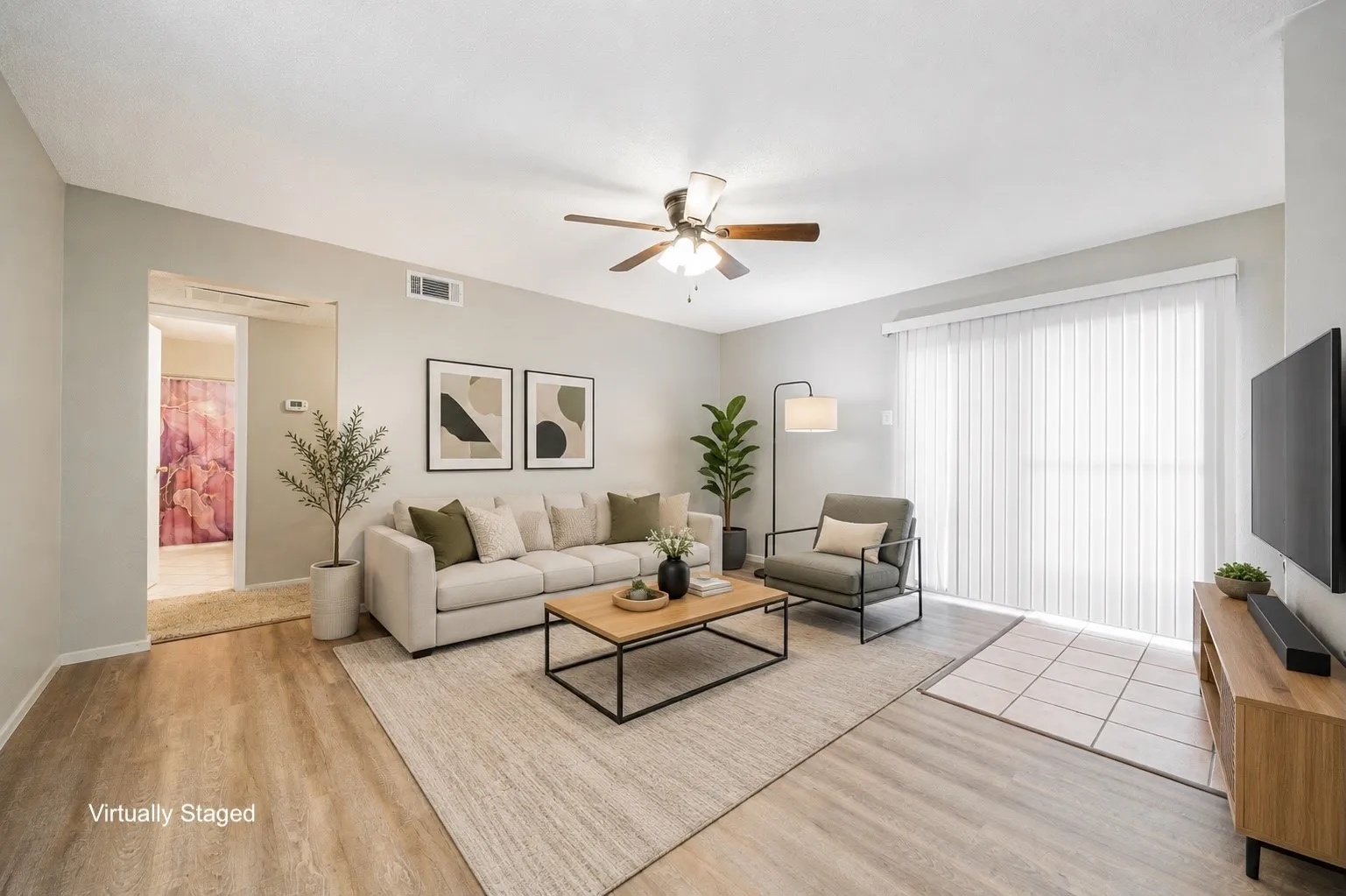 Spacious living area featuring wood-finish flooring, a ceiling fan, and sliding glass doors with vertical blinds