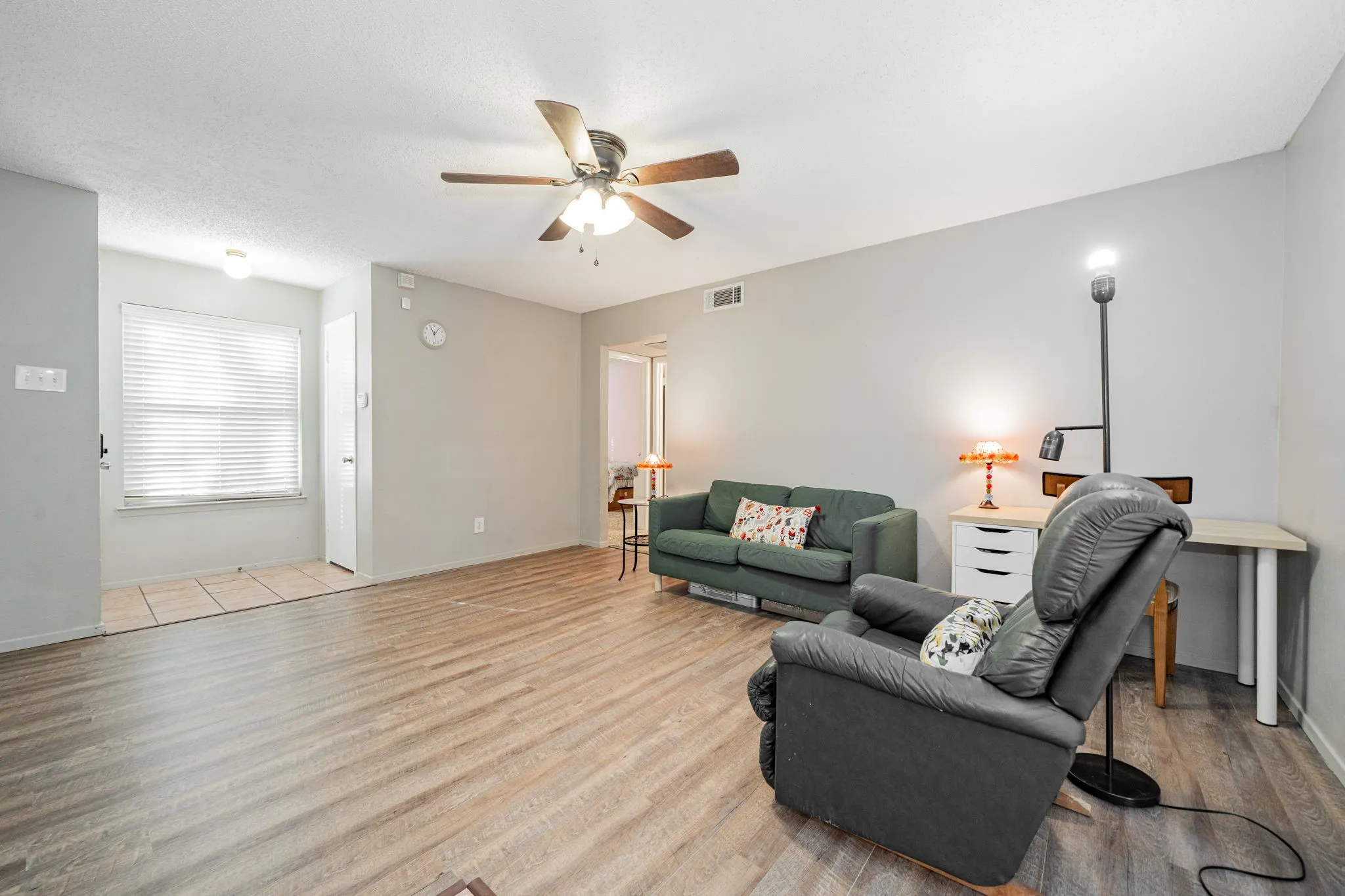 Living area featuring wood-finish flooring, a ceiling fan with integrated lighting, and neutral wall tones