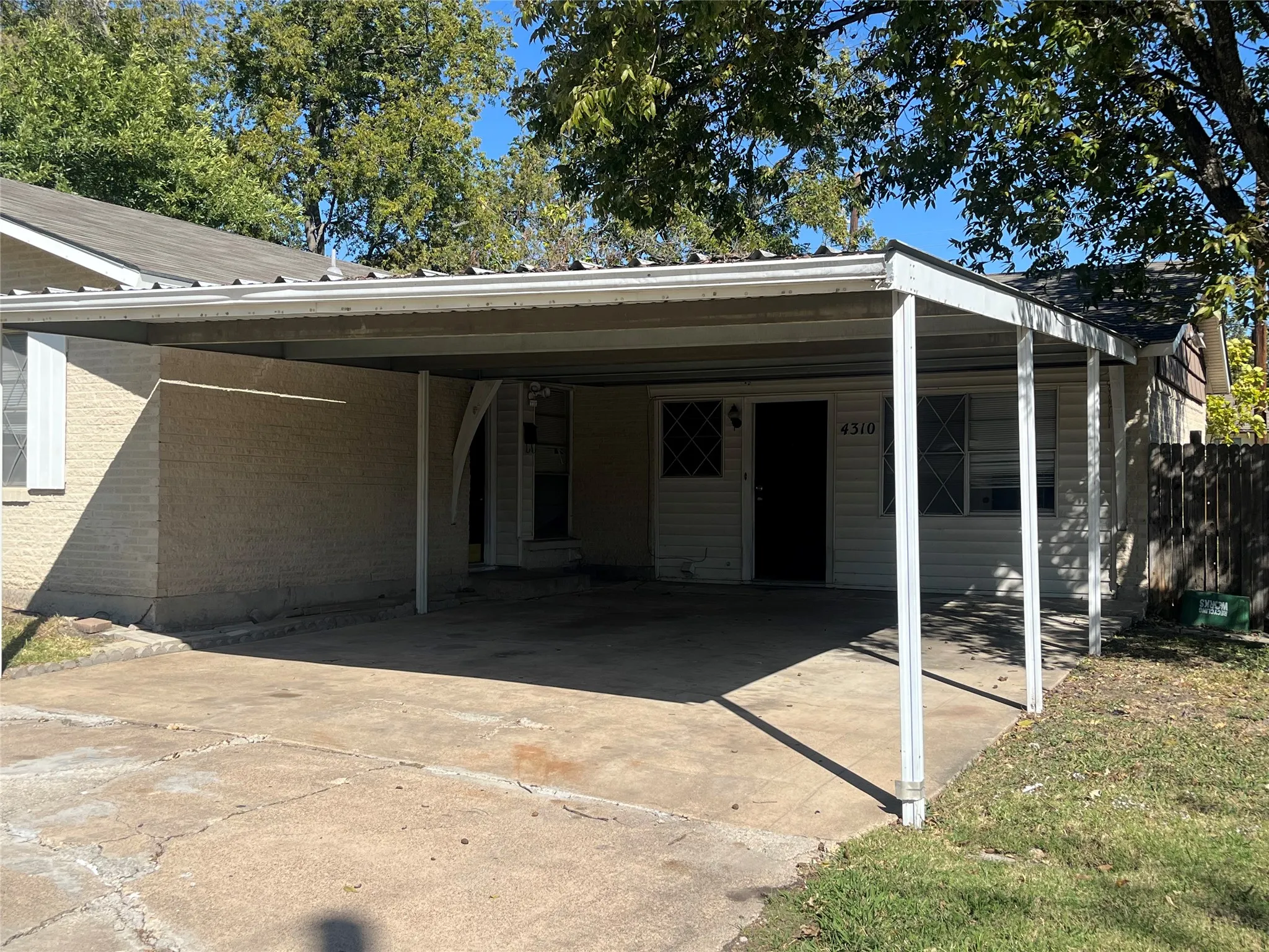 Exterior featuring a covered carport, light-colored brick siding, white horizontal siding, and a dark entry door