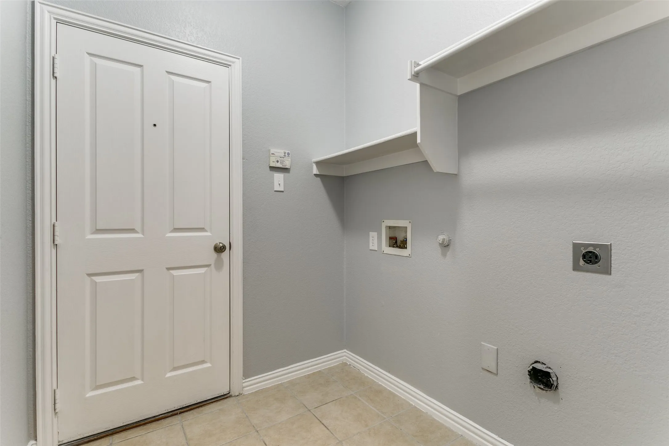 Utility room featuring light gray walls and tiled flooring
