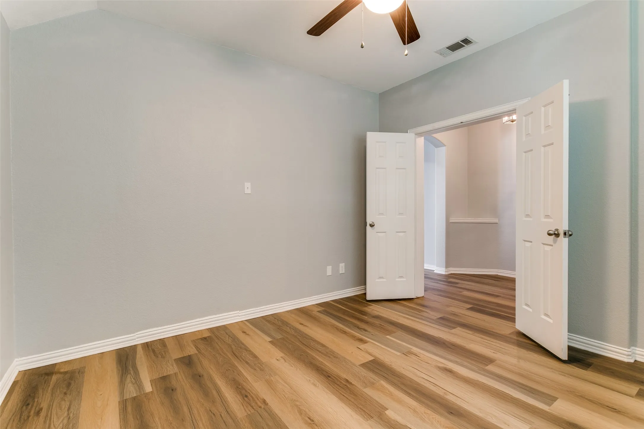 Room featuring wood-finish flooring, light grey walls, and white baseboards