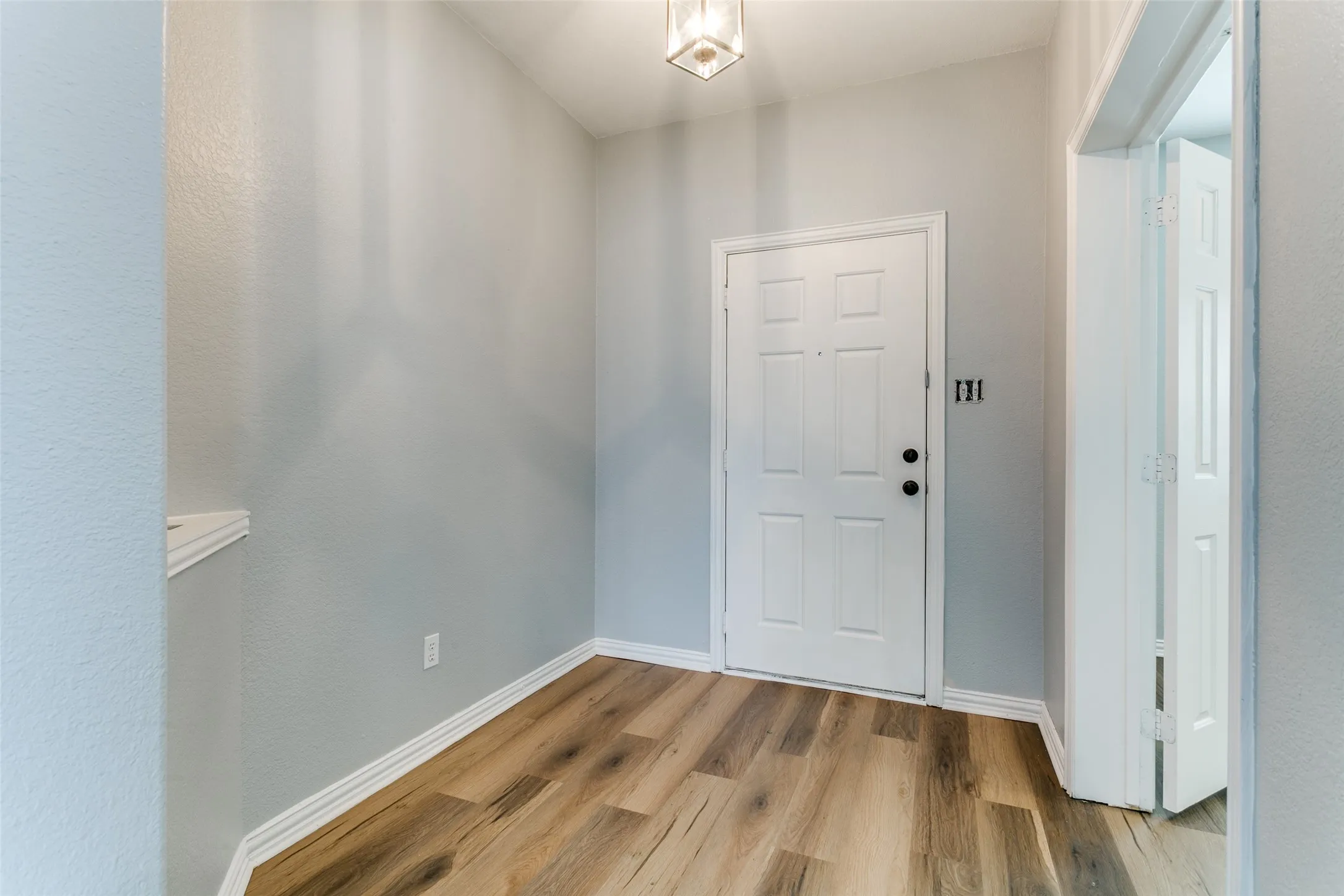 Entryway featuring wood-finish flooring, light grey wall paint, and white trim