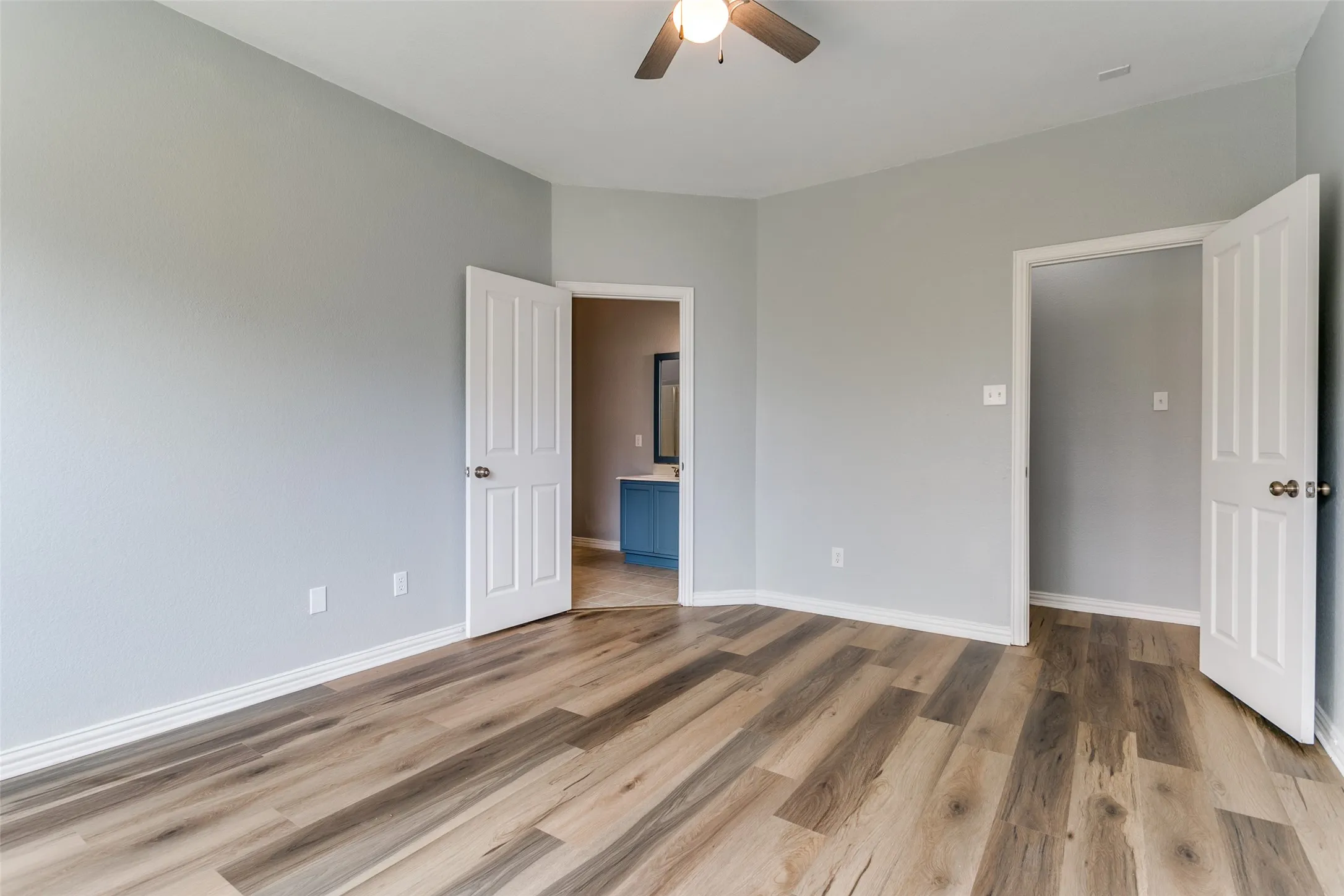 Spacious room featuring wood-finish flooring, light gray walls, and white trim