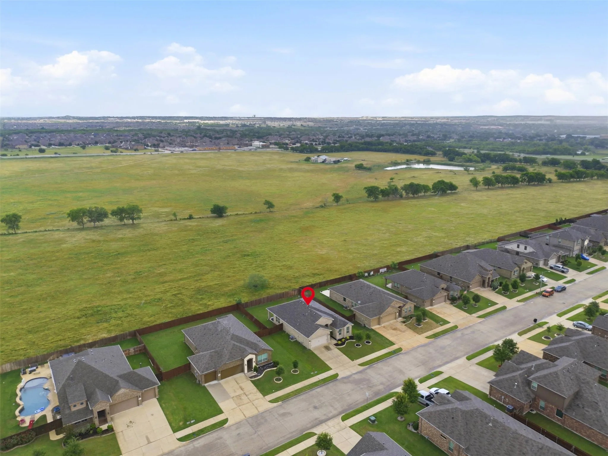Residential street with single-family homes backing onto an expansive green field
