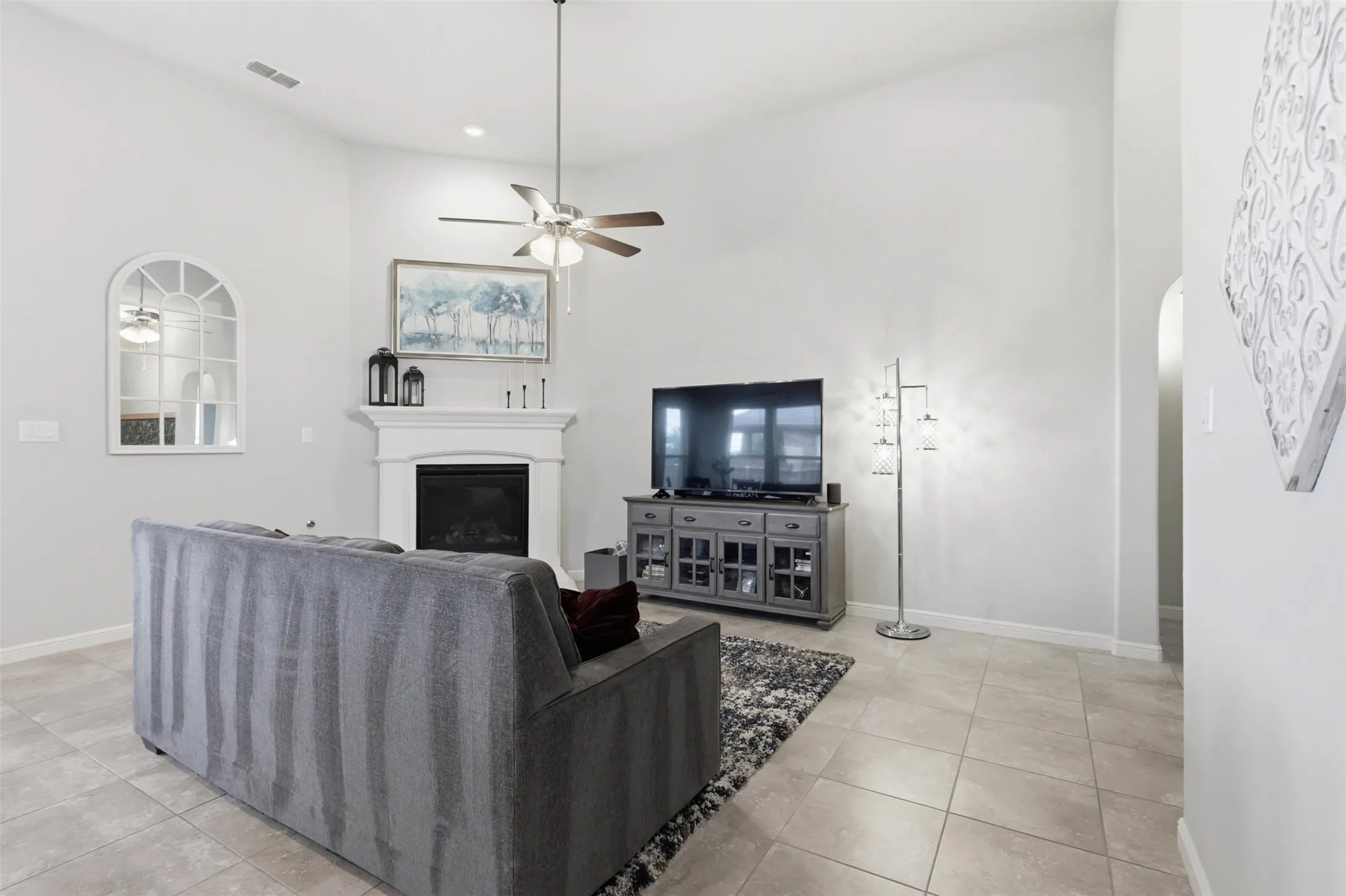 Vaulted ceiling living space featuring tile flooring, a fireplace with a white mantel, and recessed lighting