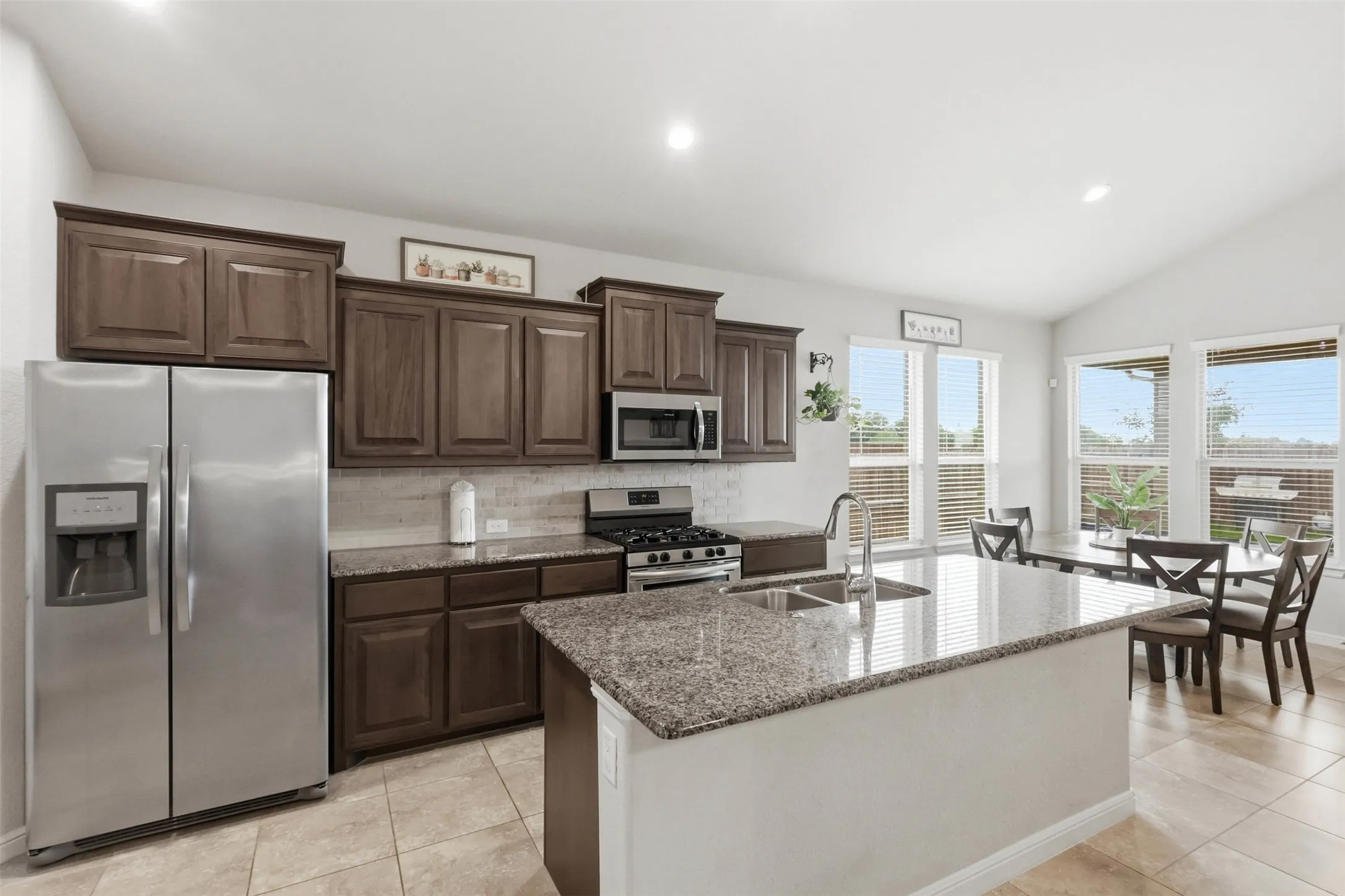 Kitchen featuring an island with a double basin sink, granite countertops, and dark wood cabinetry