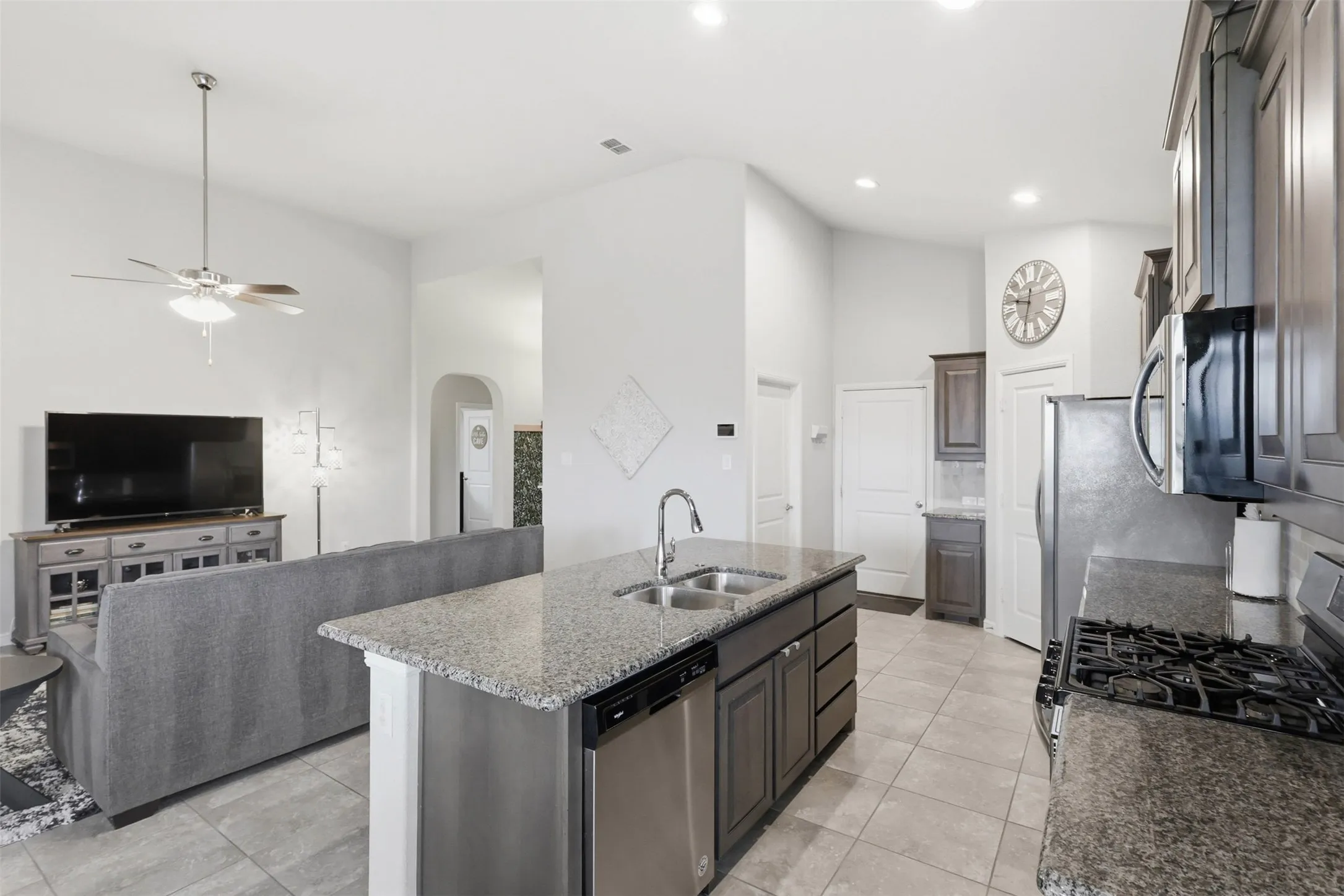 Kitchen island featuring a dual basin stainless steel sink, a chrome gooseneck faucet, and a stainless steel dishwasher