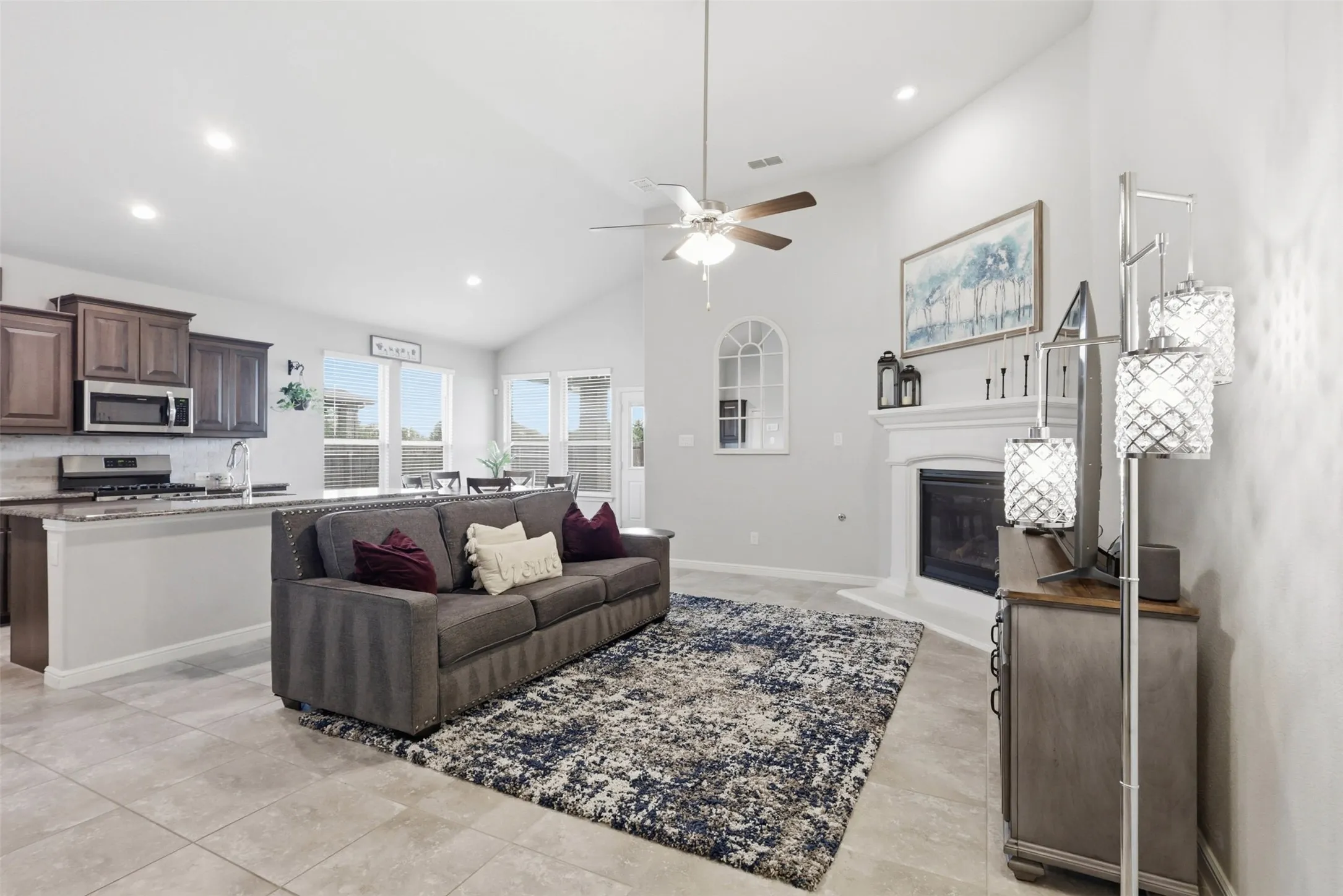 Open-concept living space featuring vaulted ceilings, a built-in fireplace, and tile flooring