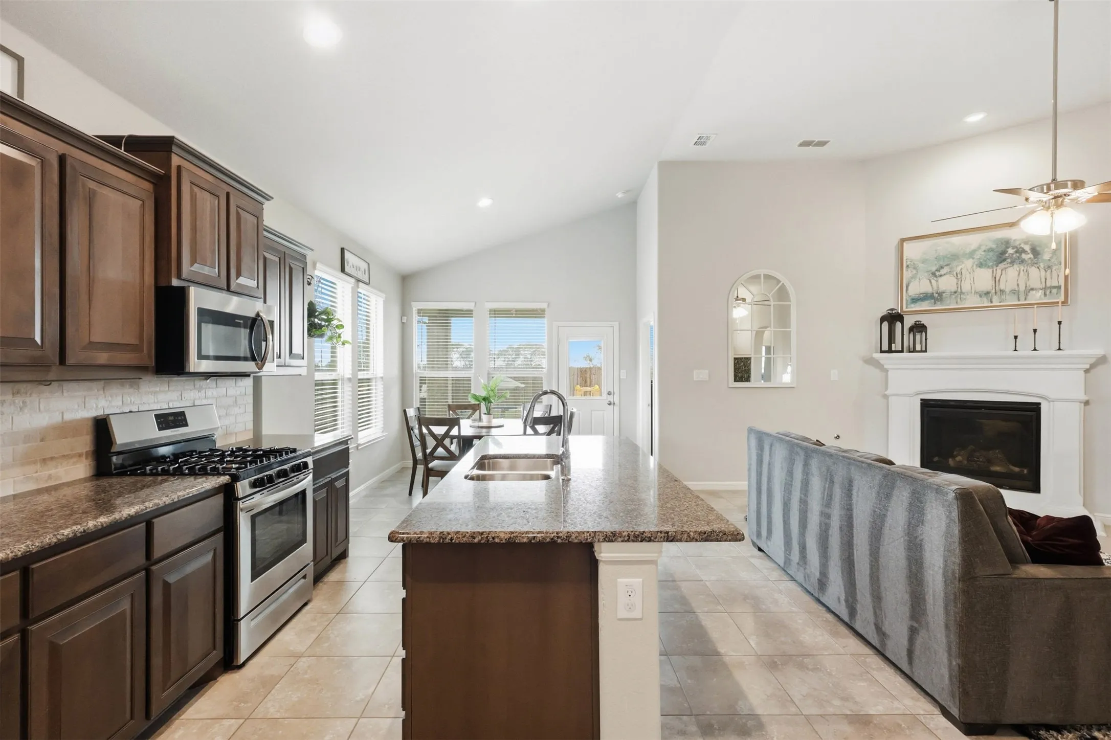 Open-concept living space featuring a kitchen with dark wood-finish cabinetry, granite countertops, and stainless steel appliances
