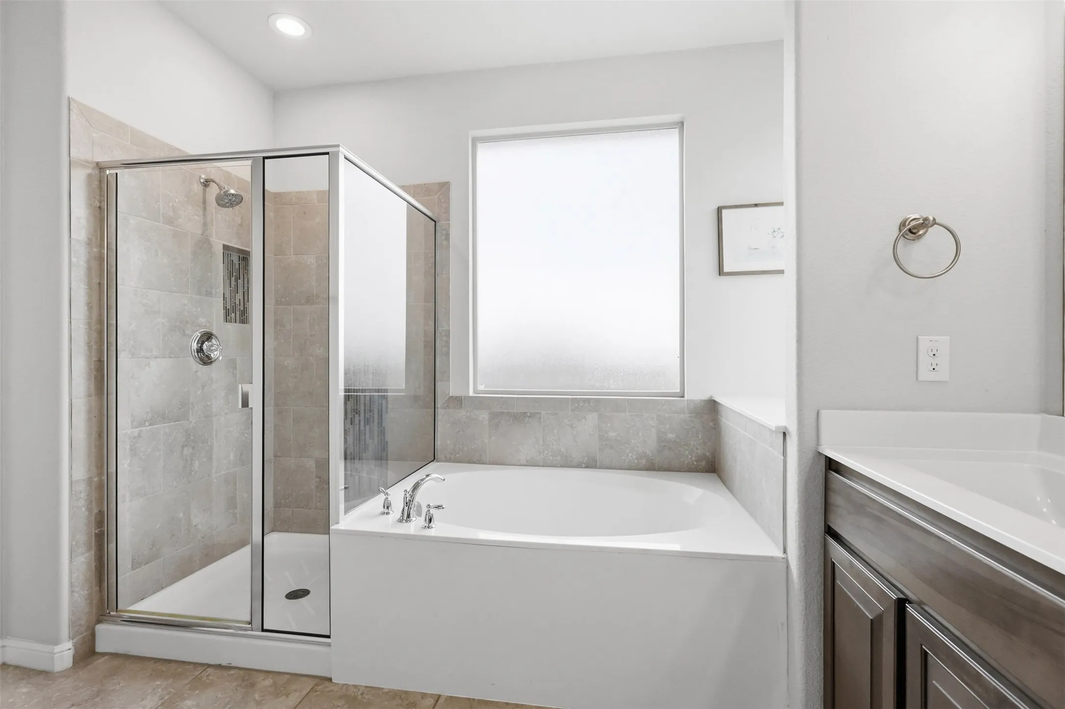 Bathroom featuring a frameless glass shower enclosure with tile surround, a built-in bathtub with deck-mounted fixtures, and a frosted window