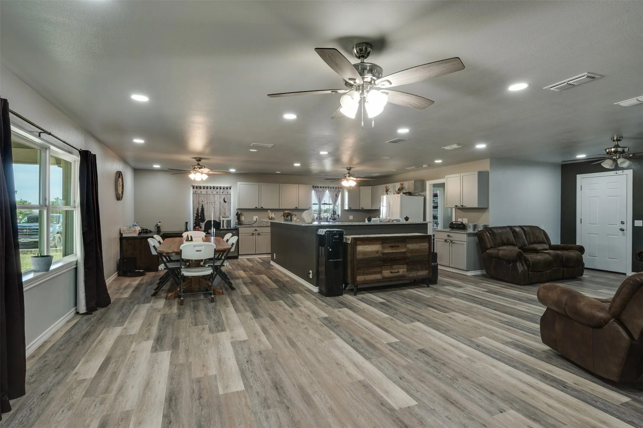 View from the entry showing the open floor plan with the Kitchen being the true center of the home.  All updated lighting and flooring.  Solid surface countertops.  Updated windows.