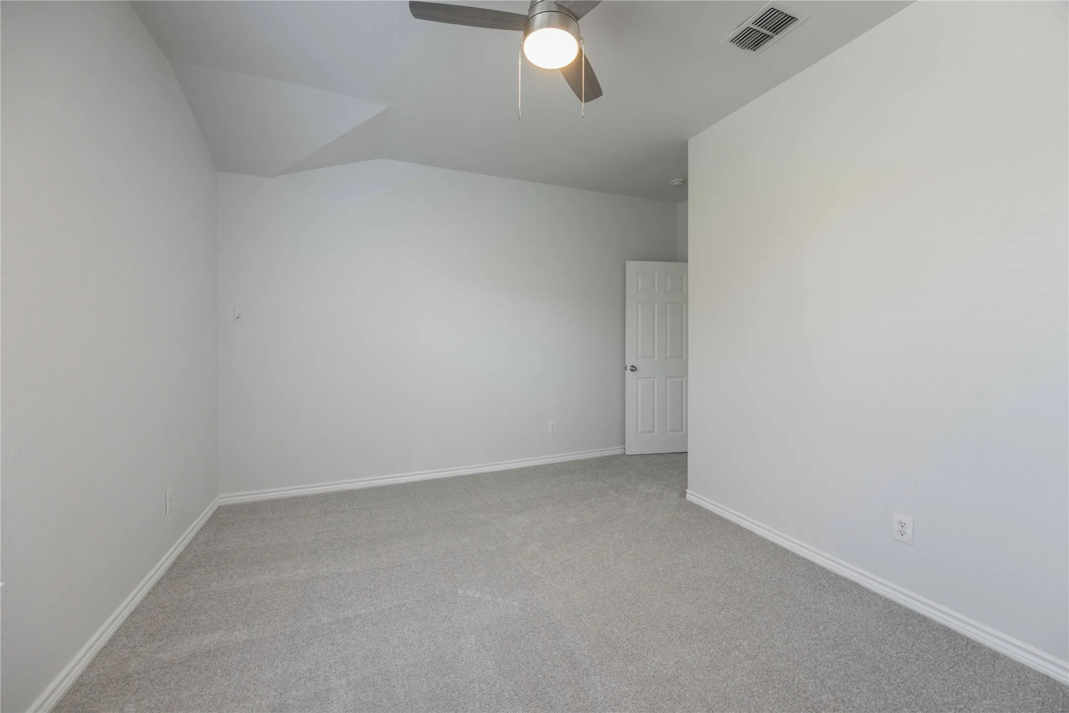 Carpeted interior room featuring light gray walls, white baseboards, and a ceiling fan with integrated lighting