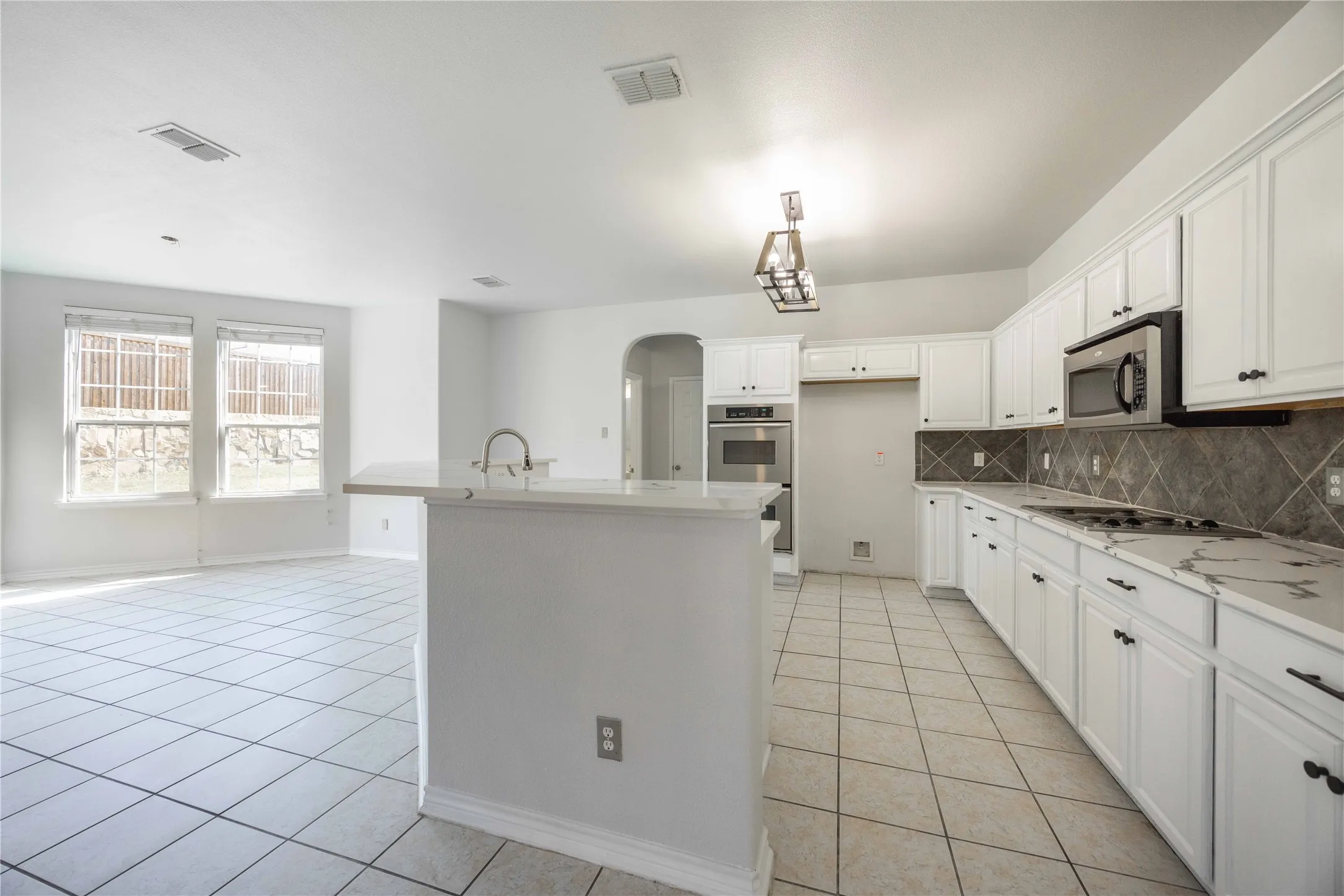 Kitchen featuring white cabinetry with dark hardware, stone-look countertops, and a subway tile backsplash