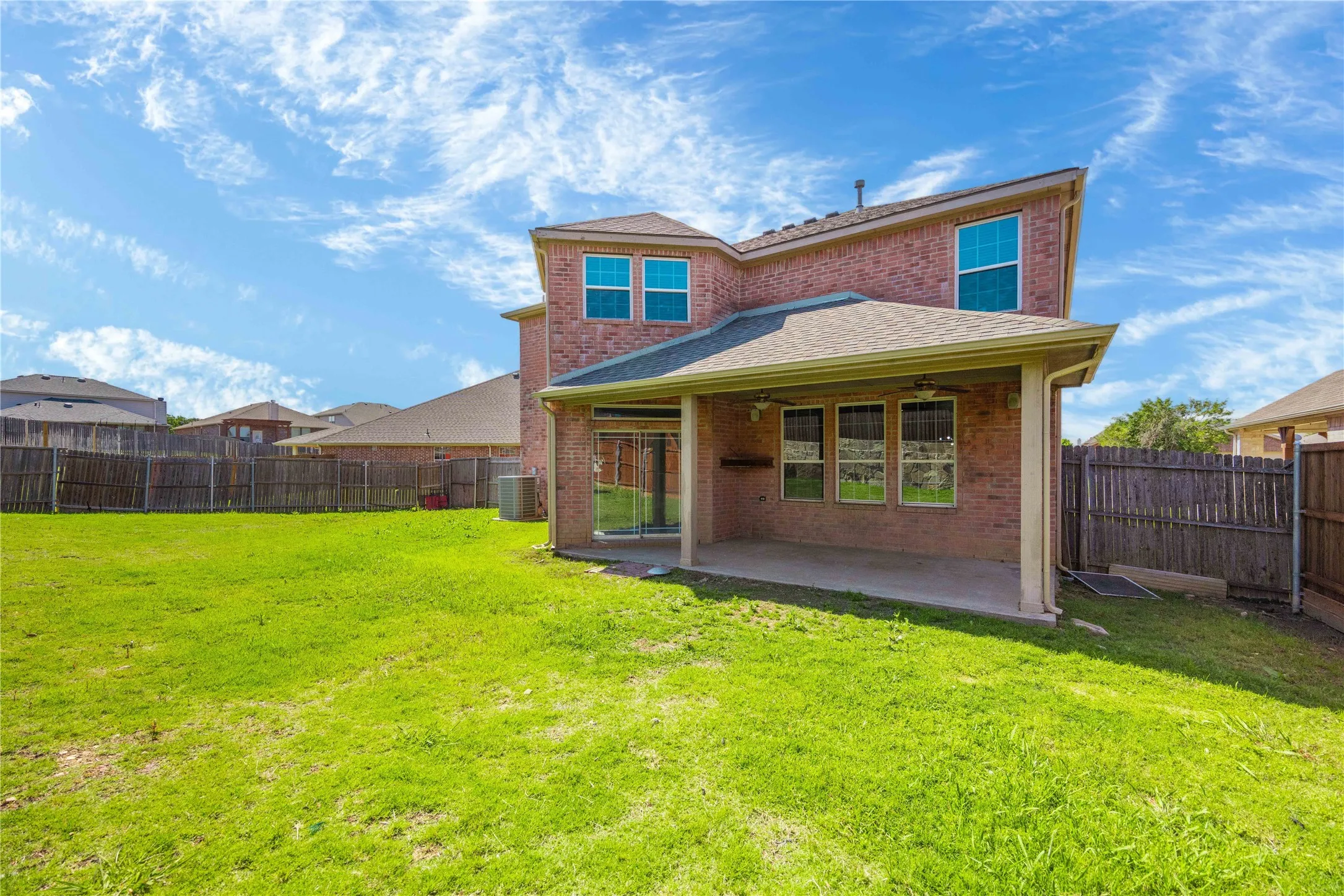 Expansive green lawn with a covered patio featuring a concrete surface, recessed lighting, and ceiling fans