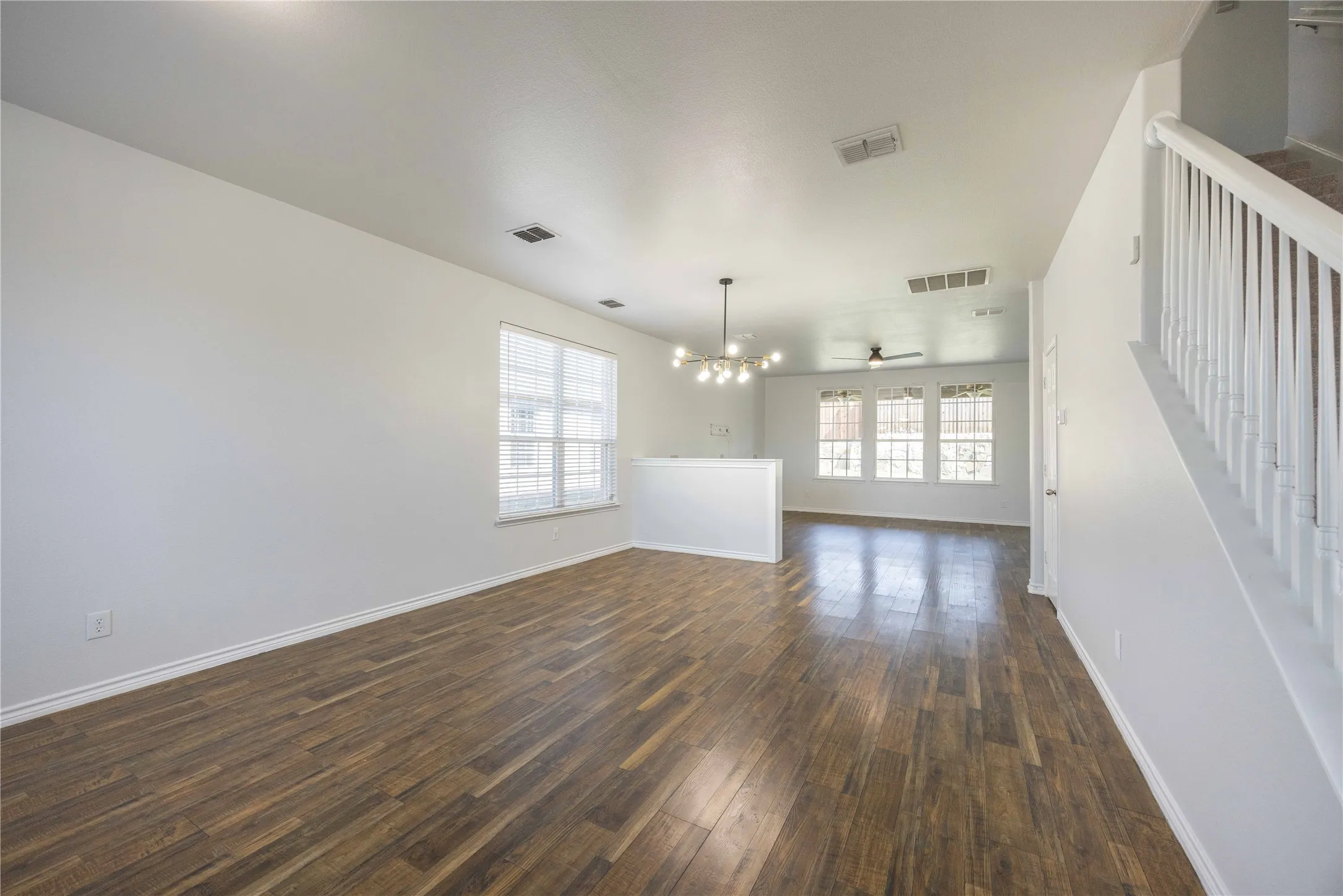 Spacious main living area featuring wood-finish flooring, white baseboards, and bright white walls