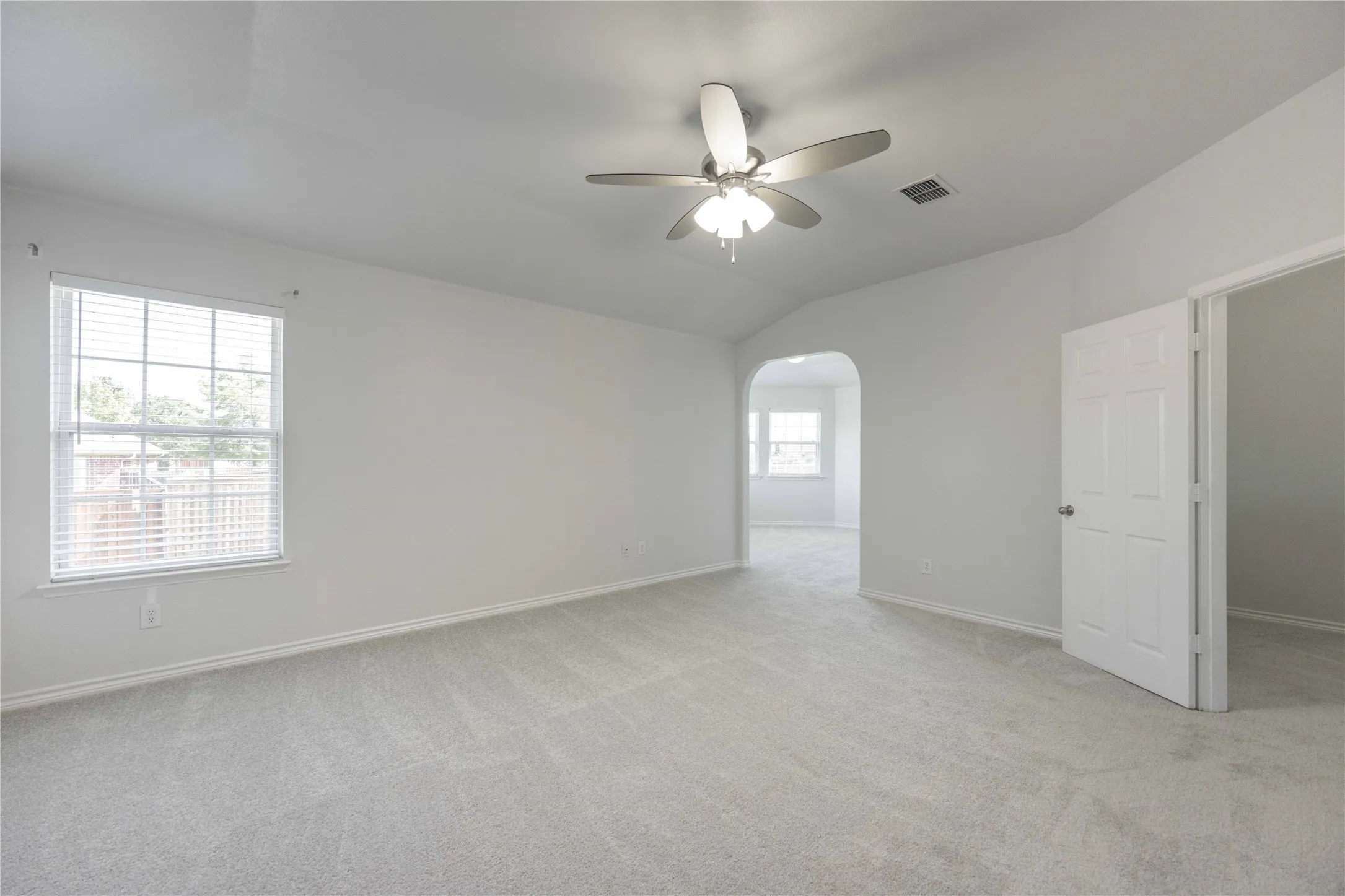 Spacious room featuring vaulted ceilings and light gray carpeting