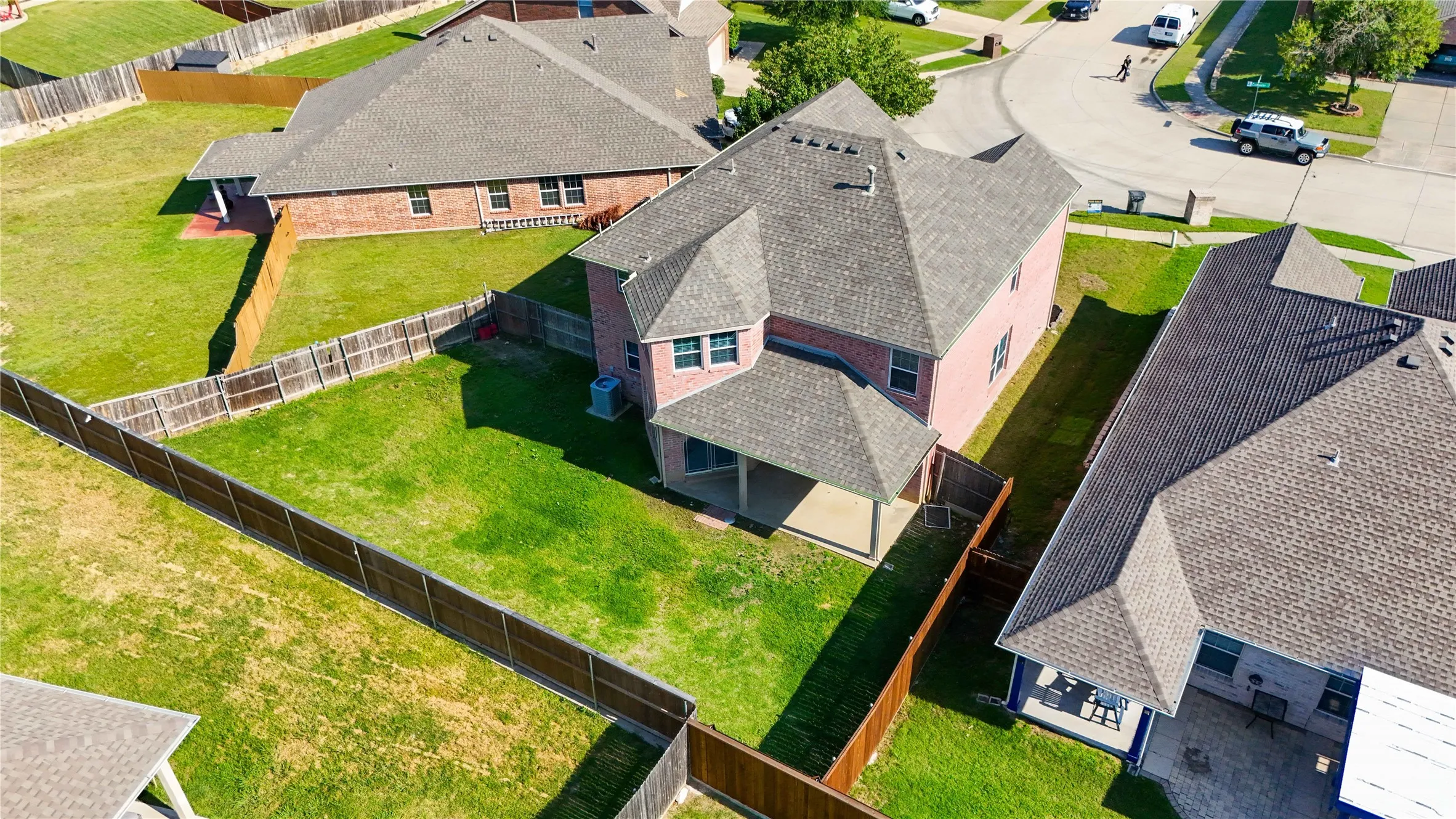 Spacious backyard featuring a manicured lawn, full privacy fencing, and a covered patio area