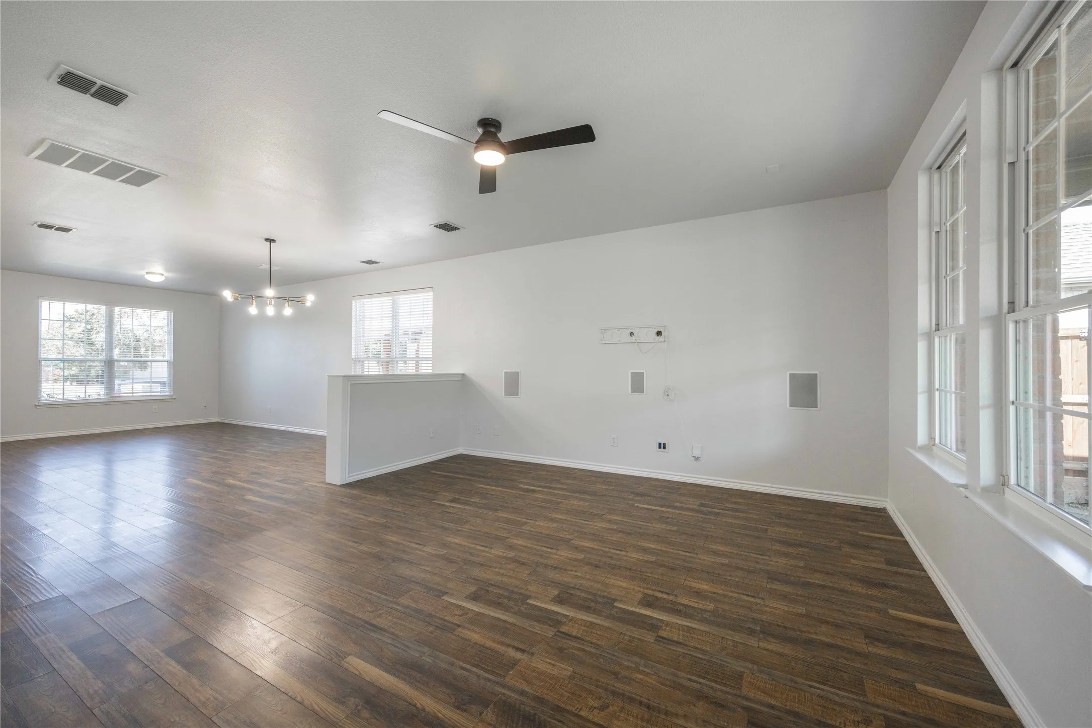 Spacious interior featuring wood-finish flooring, white walls, and multiple windows