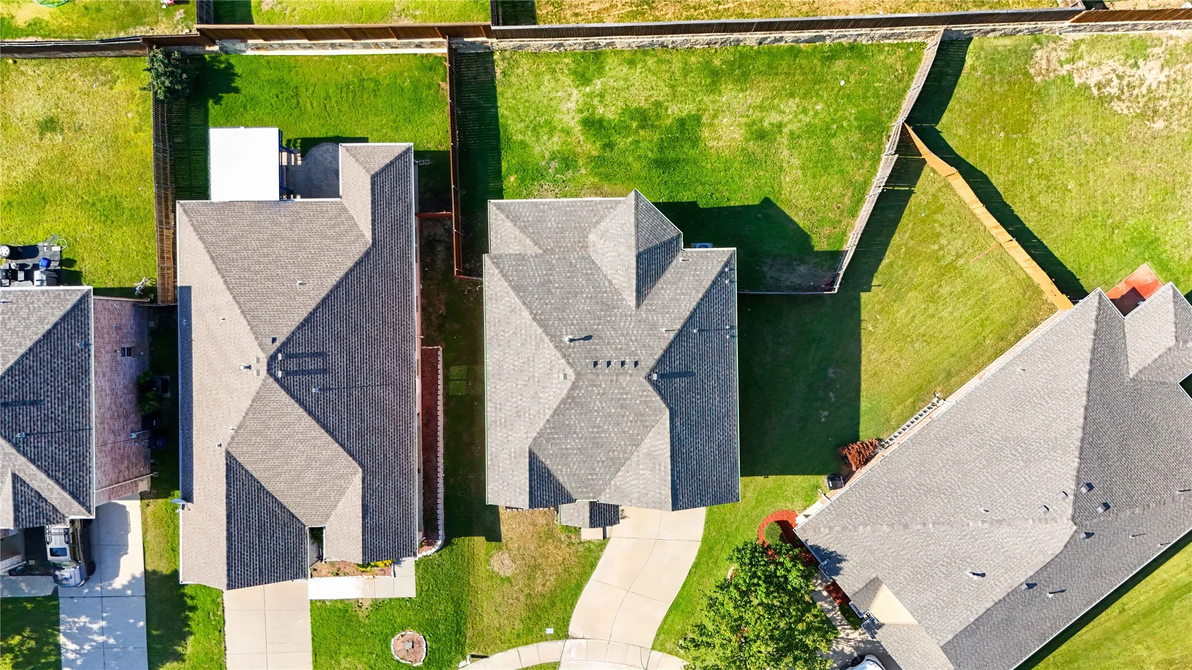 Residential property featuring a shingle roof and a spacious, fenced backyard with manicured lawns