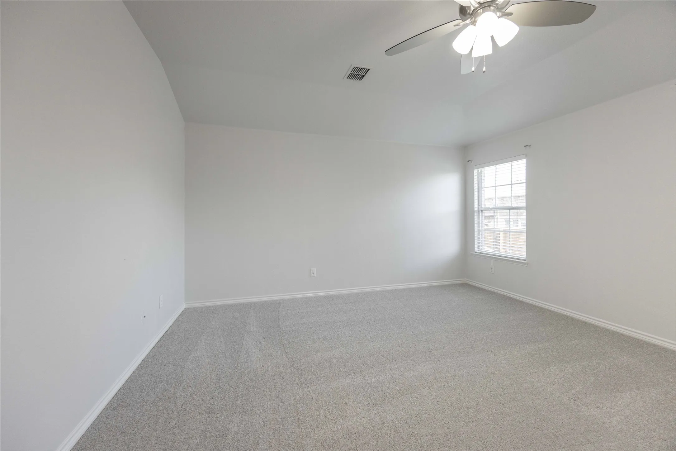 Carpeted room with a ceiling fan light fixture