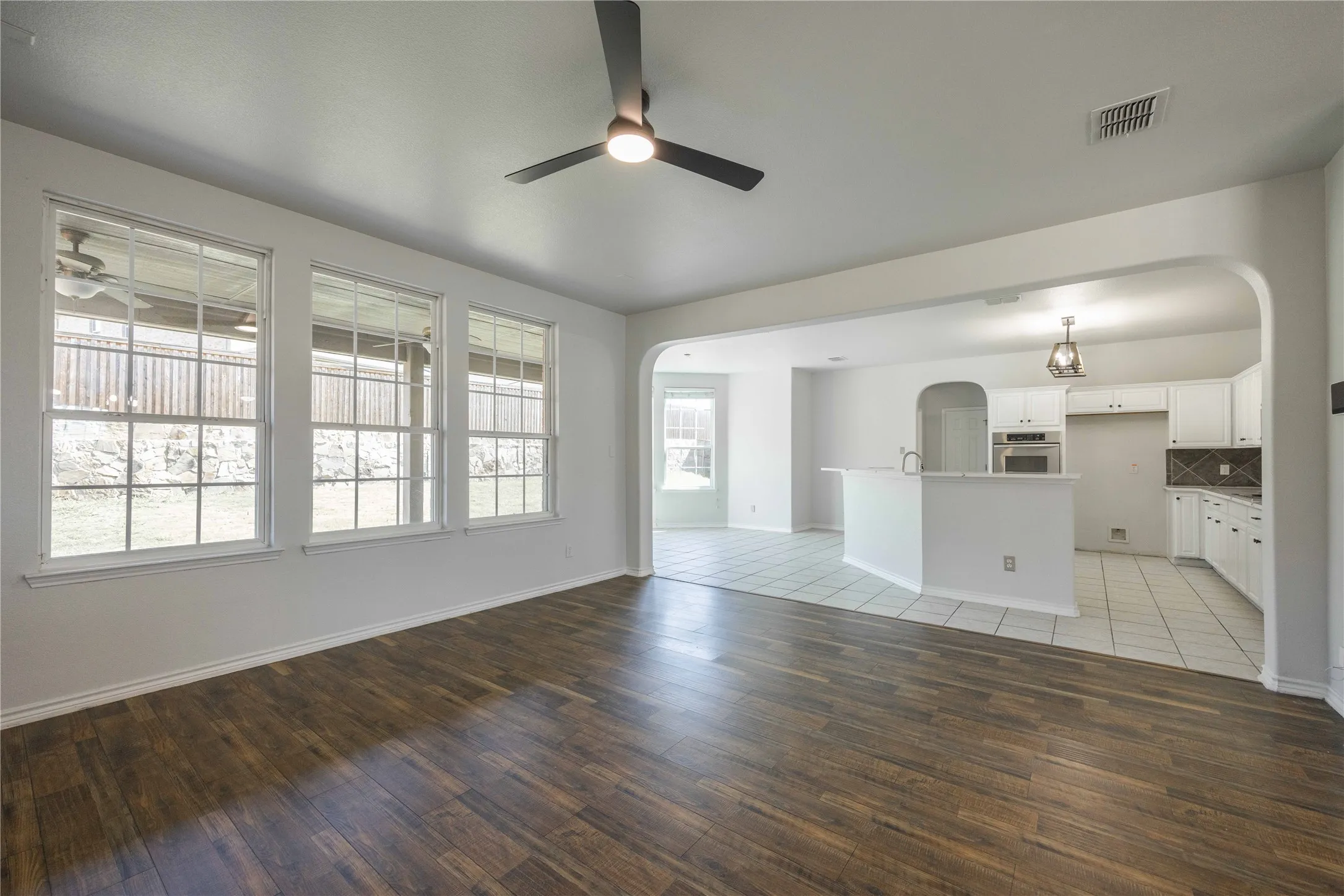 Expansive living area featuring wood-finish flooring and three large windows
