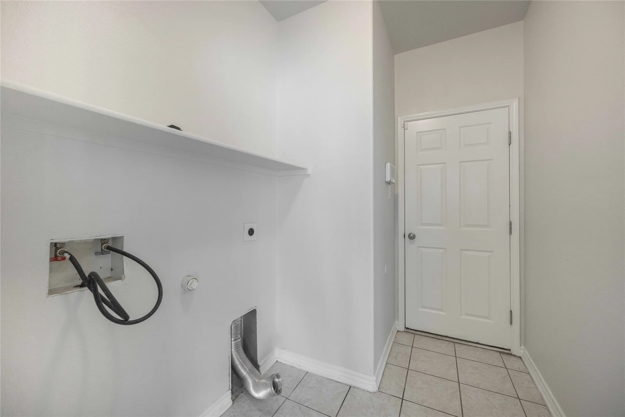 Utility area featuring a paneled door, built-in shelving, tile flooring, and light gray wall paint