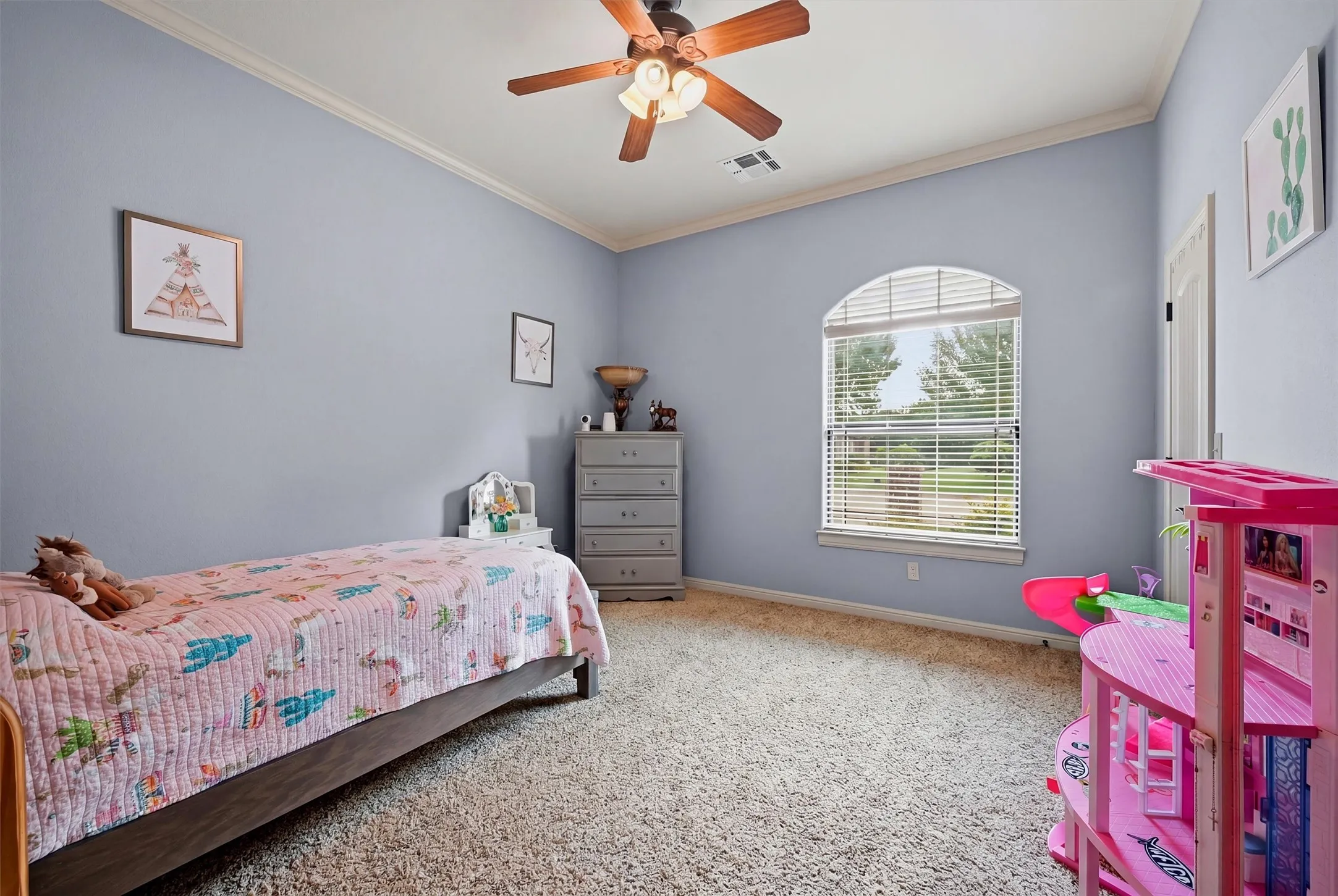 Spacious room featuring vaulted ceilings, a ceiling fan, crown molding, an arched window with blinds, and carpeting