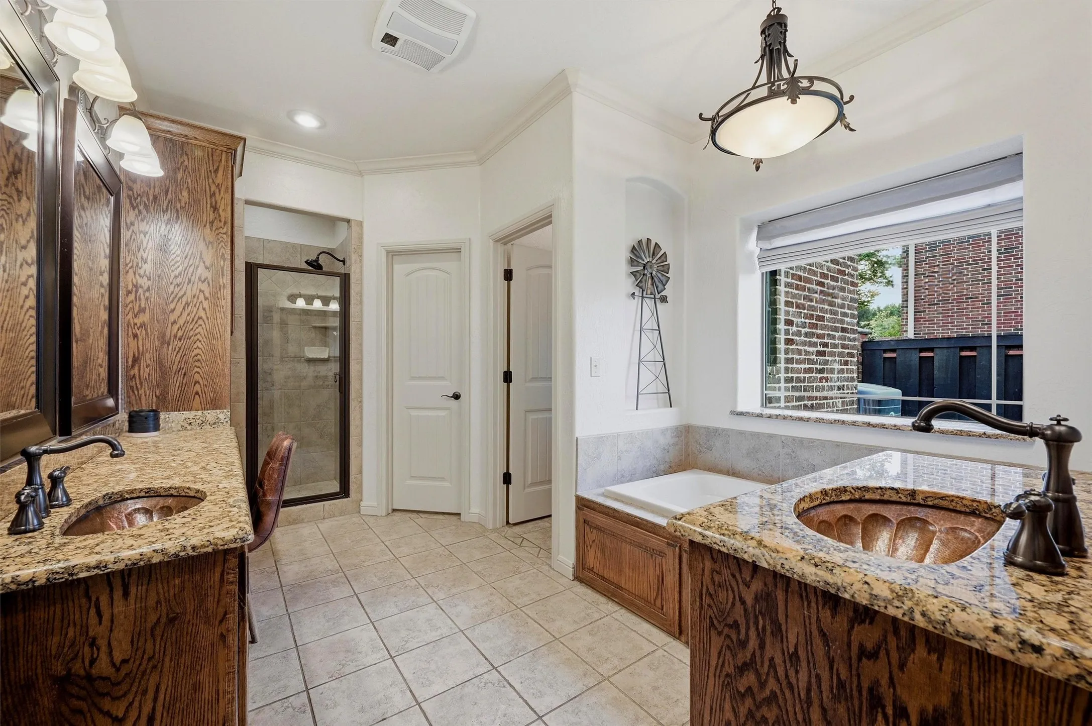 Double vanity featuring wood-finish cabinetry, granite countertops, and bronze-finish fixtures
