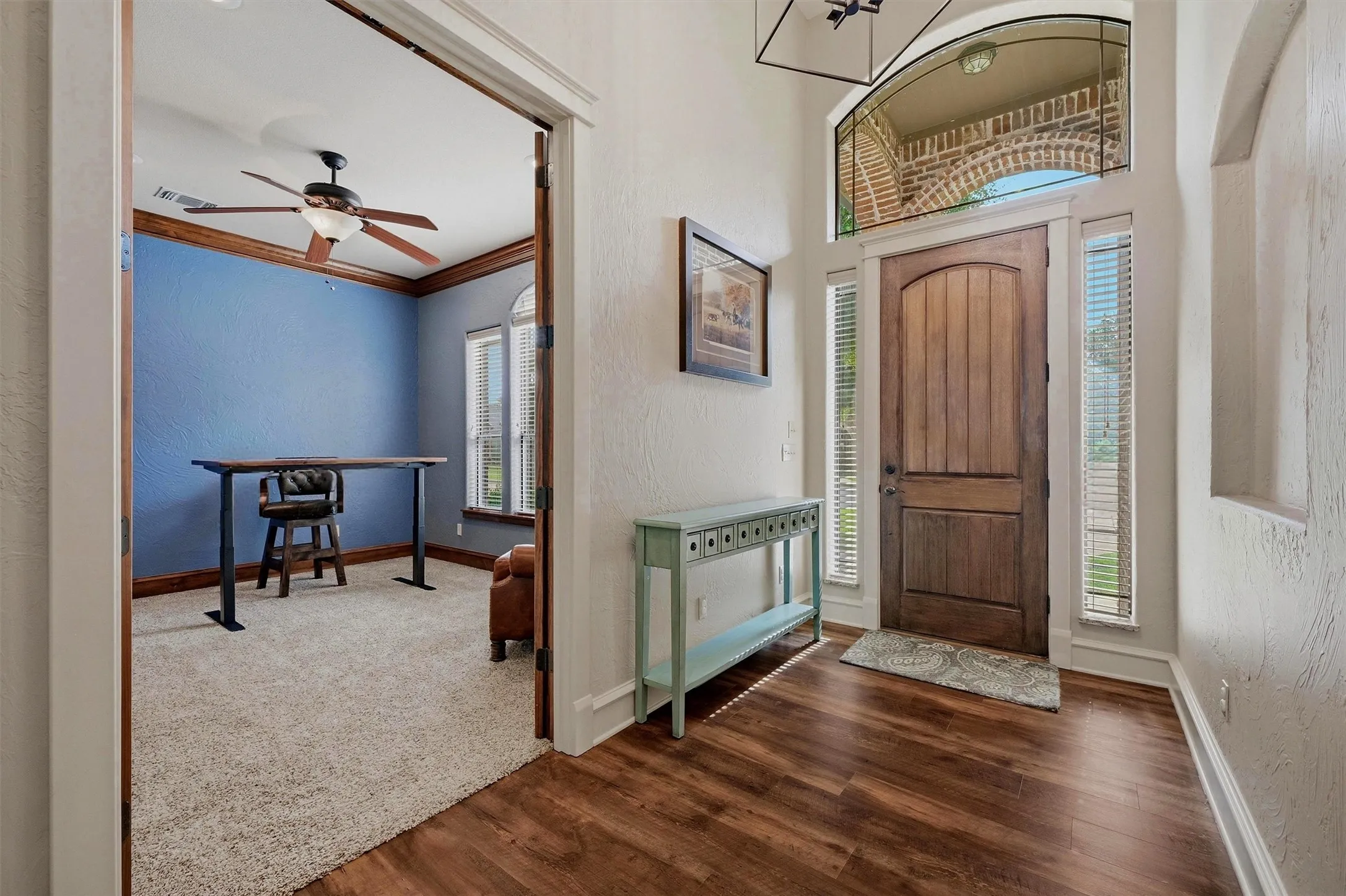 Entryway featuring wood-finish flooring and a solid wood front door with sidelight windows and an arched transom
