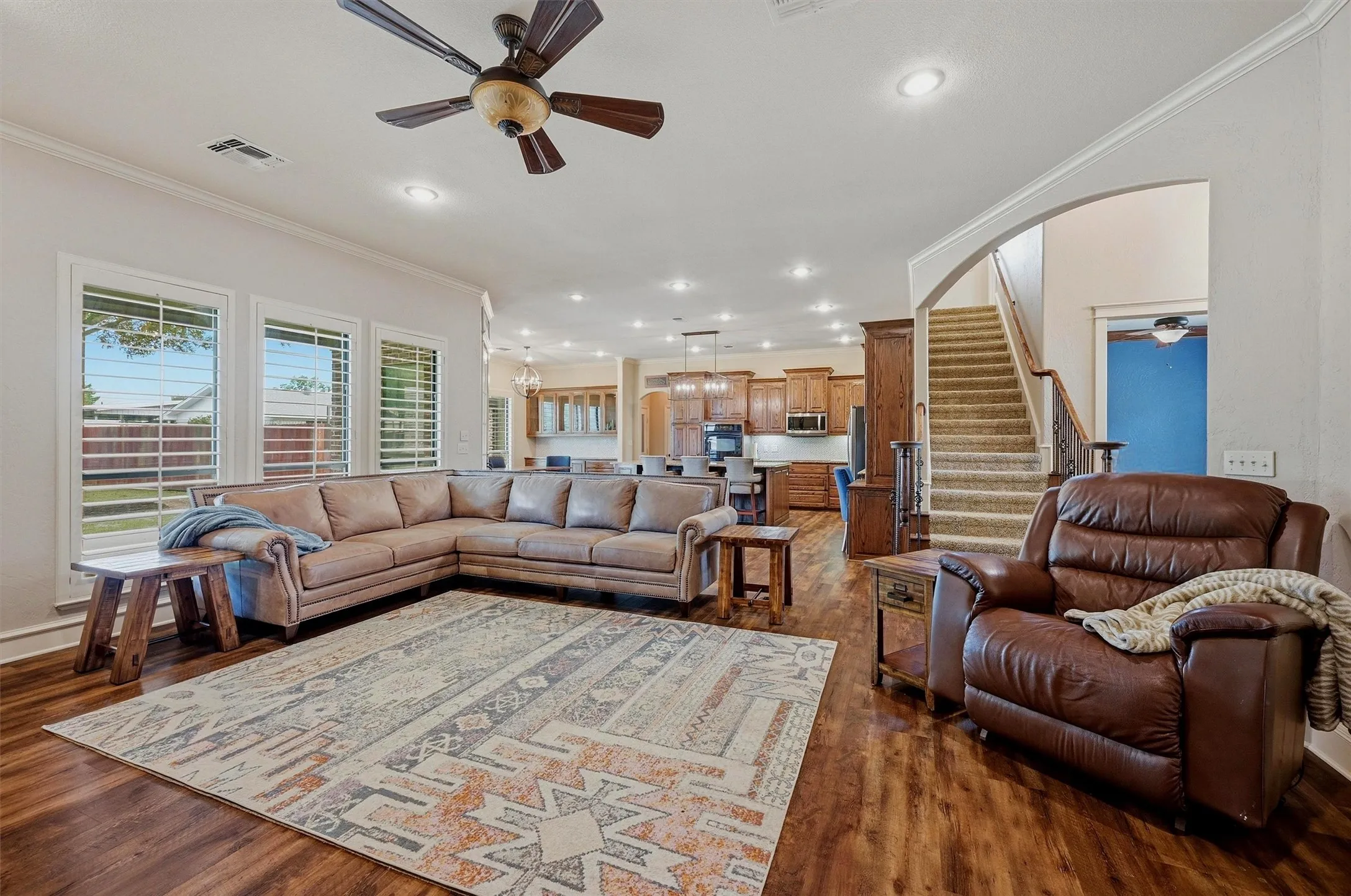 Spacious open-concept living area featuring wood-finish flooring, recessed lighting, and a ceiling fan