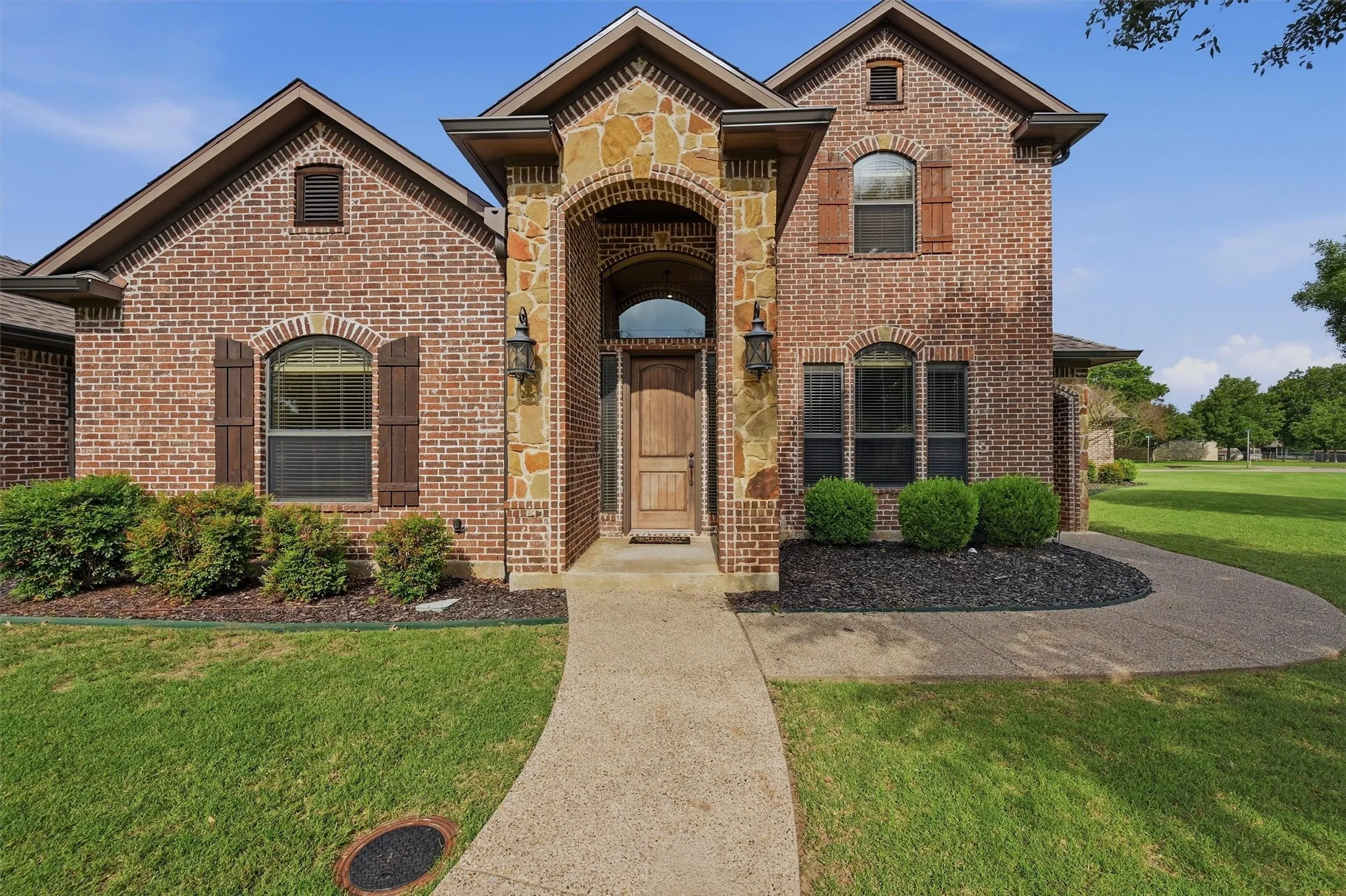 Brick and stone facade featuring an arched entryway with a solid wood door