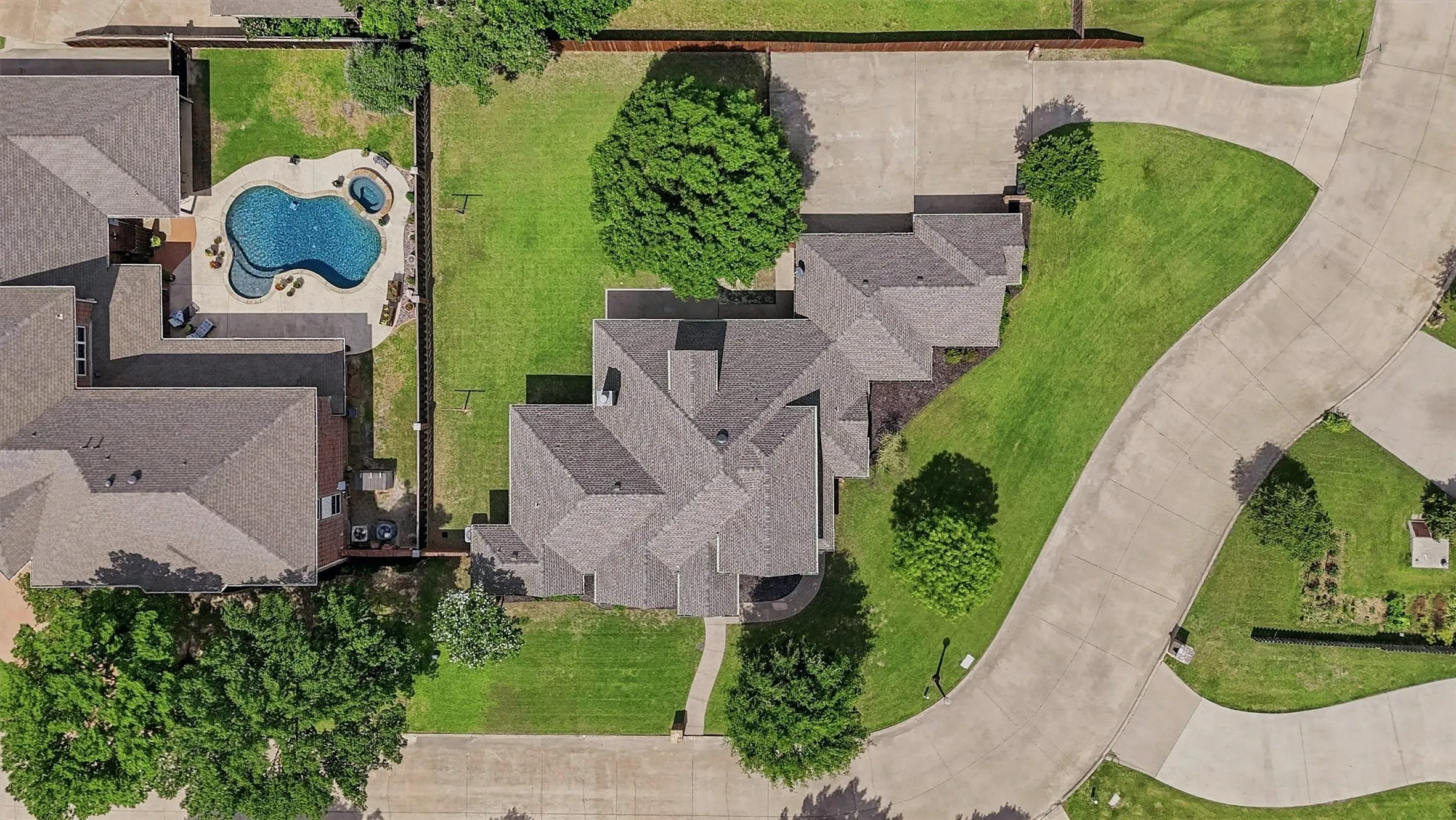 Expansive property featuring a multi-gabled roofline, mature trees, a private swimming pool, and a spa