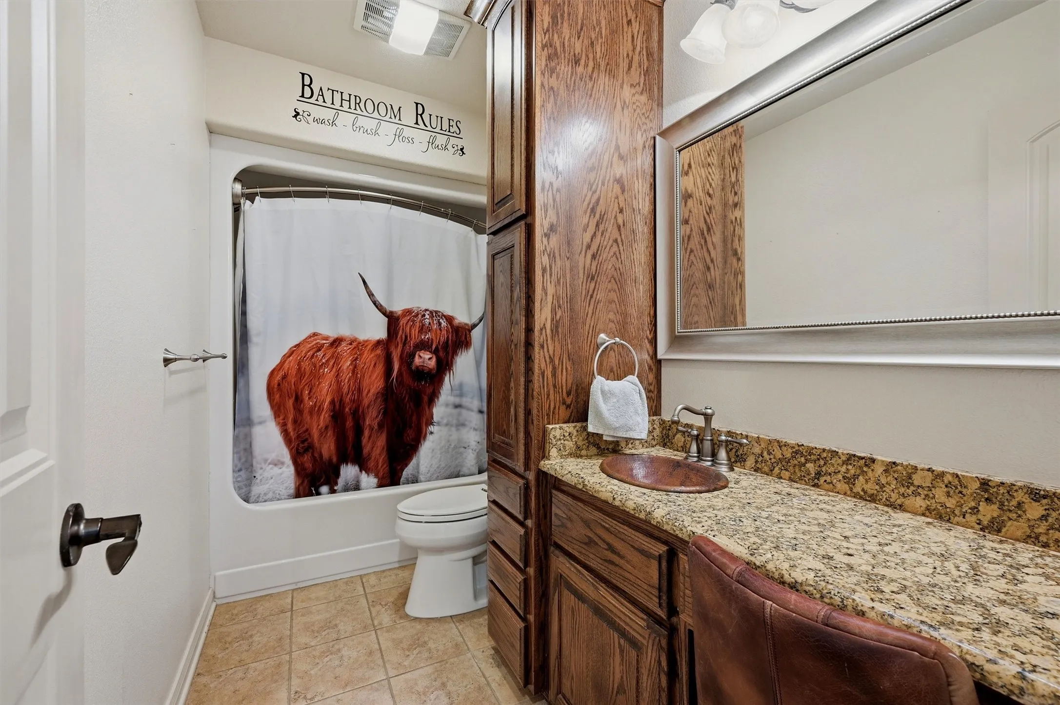 Bathroom featuring a built-in wood-finish vanity with an integrated basin sink and dual-handle faucet