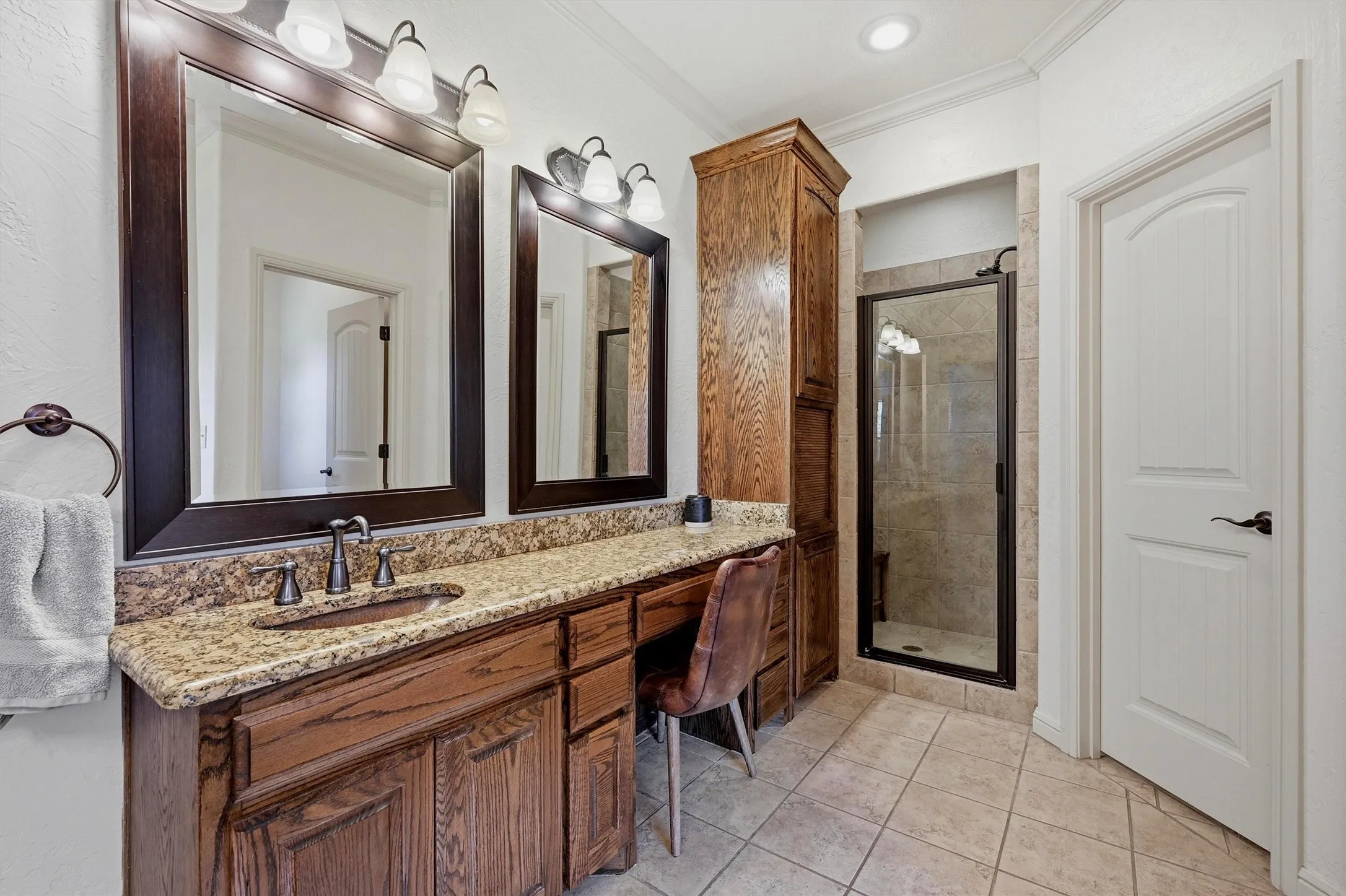 Bathroom featuring a dual vanity with a speckled countertop, integrated sink, and an expansive wood-finish cabinet