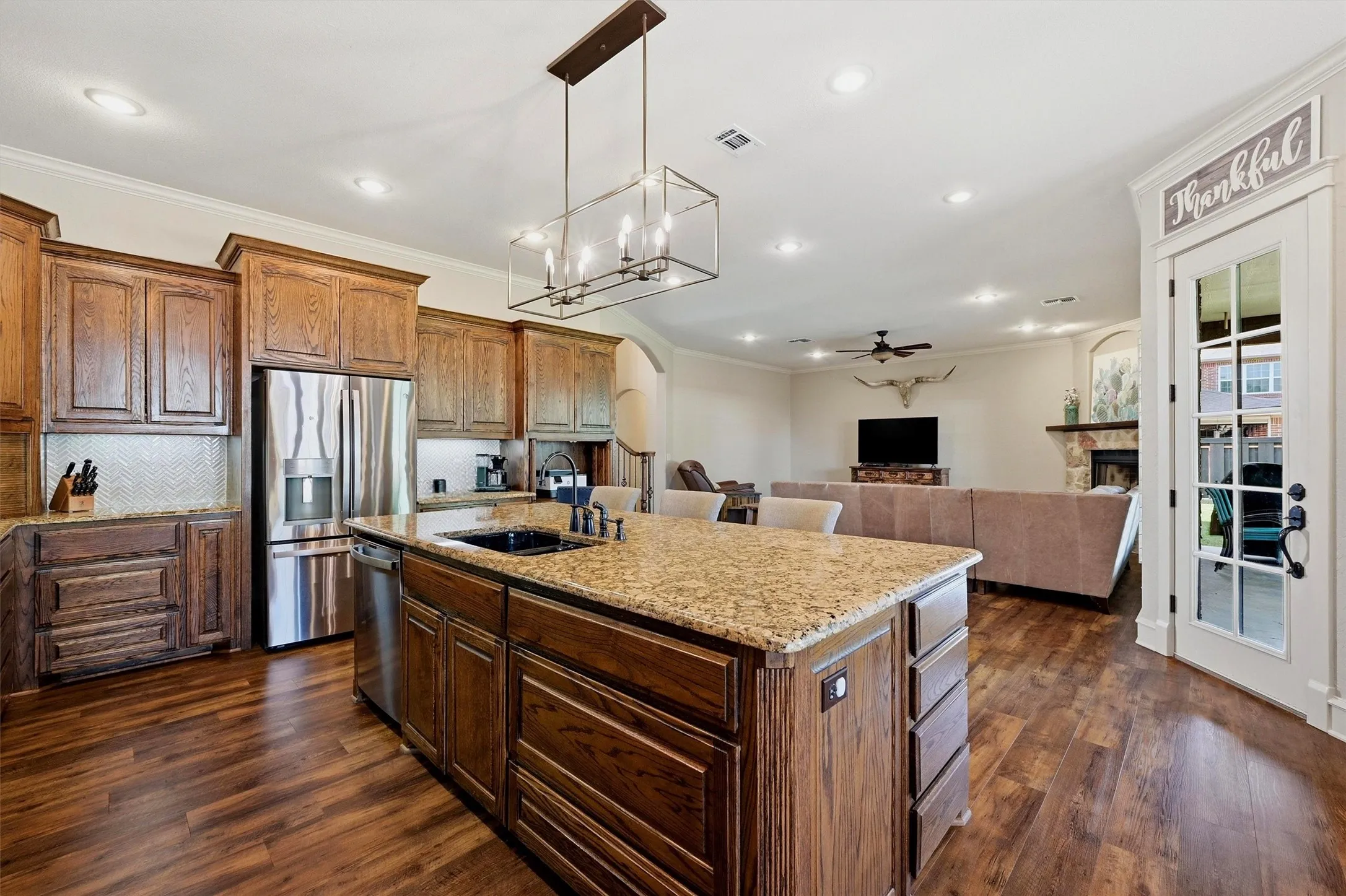 Open-concept kitchen featuring wood-finish flooring, recessed lighting, and a chandelier