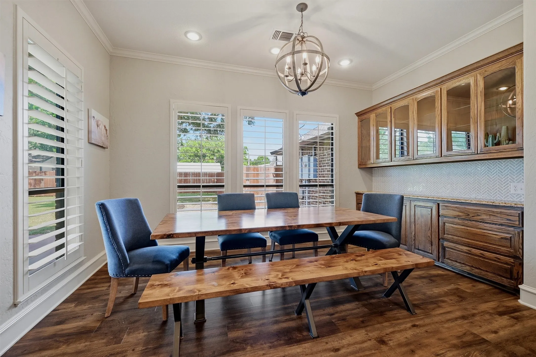 Dining area featuring wood-finish flooring, multiple windows with white plantation shutters, and recessed lighting