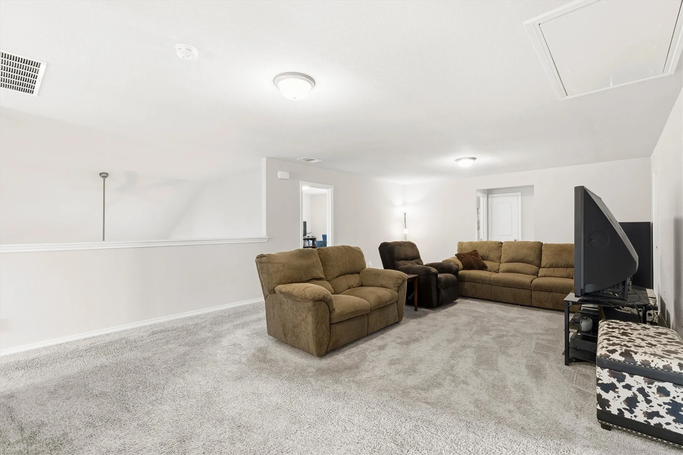 Spacious bonus room featuring light gray carpeting, recessed ceiling lighting, a white painted half-wall, and a ceiling access panel