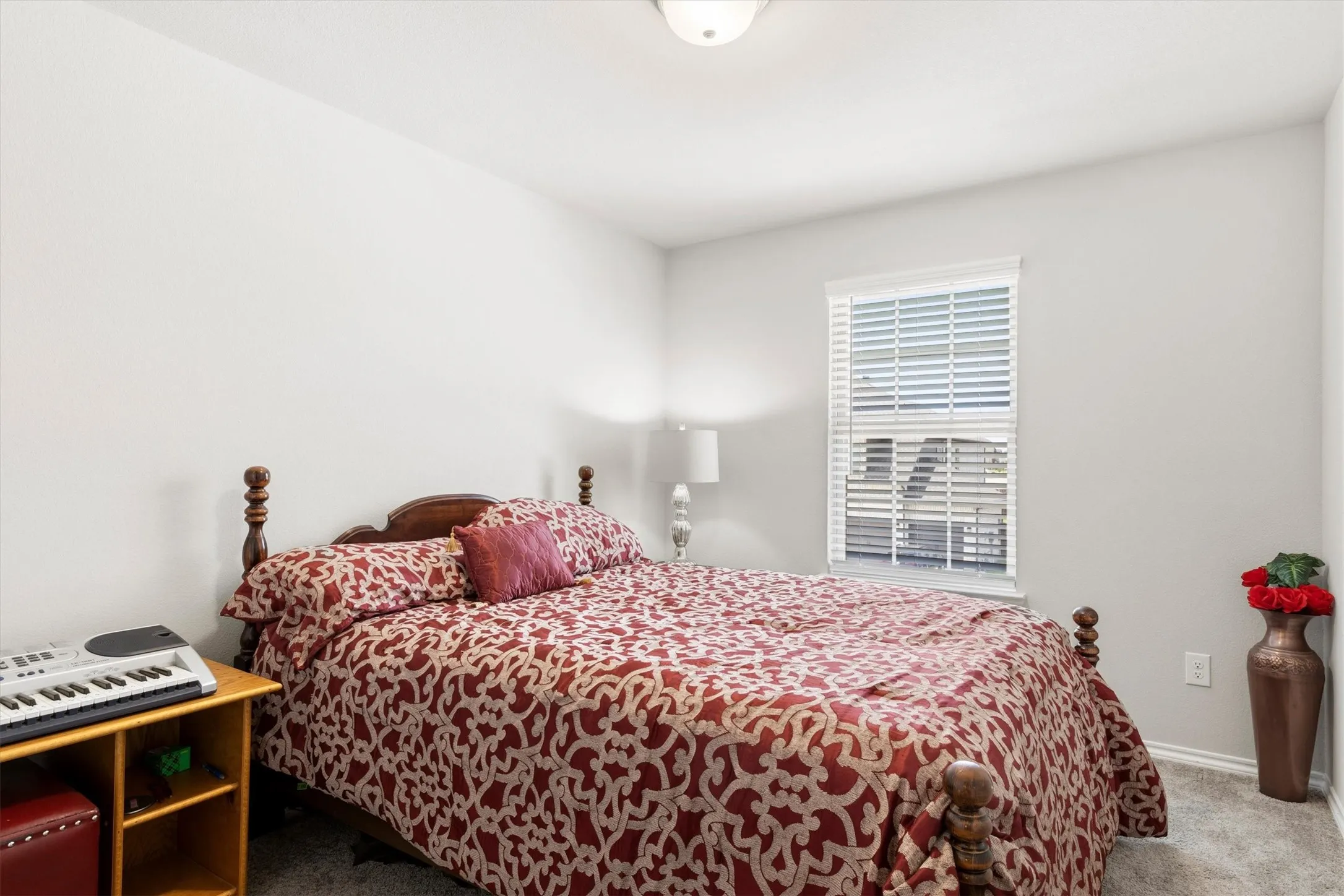 Bedroom featuring light gray walls, plush gray carpet, and a window with white blinds